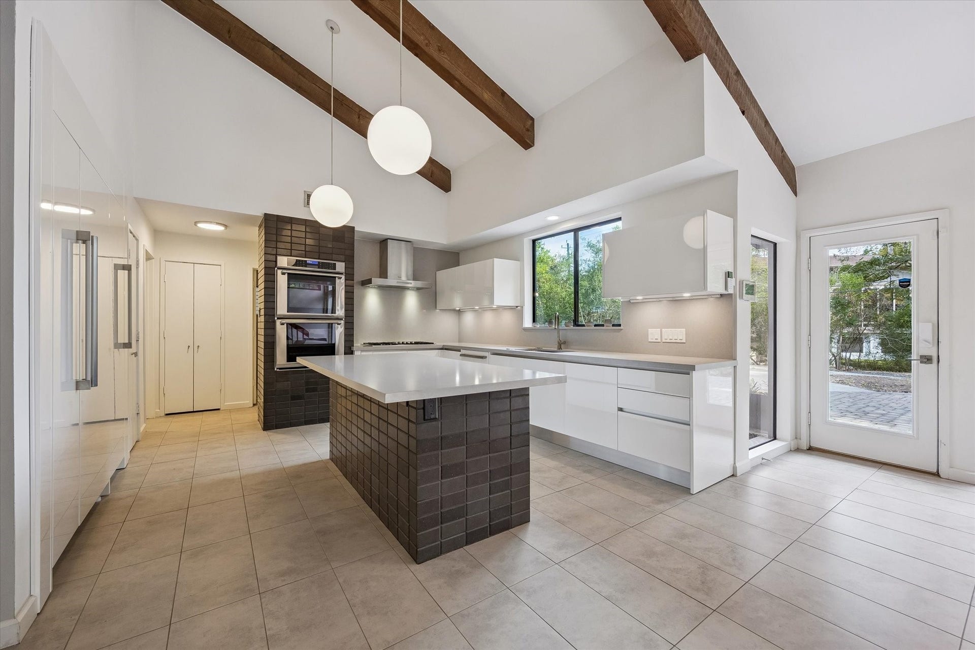 104 Gershwin Drive, Houston, TX 77079 Another view highlights the spacious center island, Thermador refrigerator/freezer, double ovens & abundant cabinetry, all complemented by exposed beams & contemporary lighting.