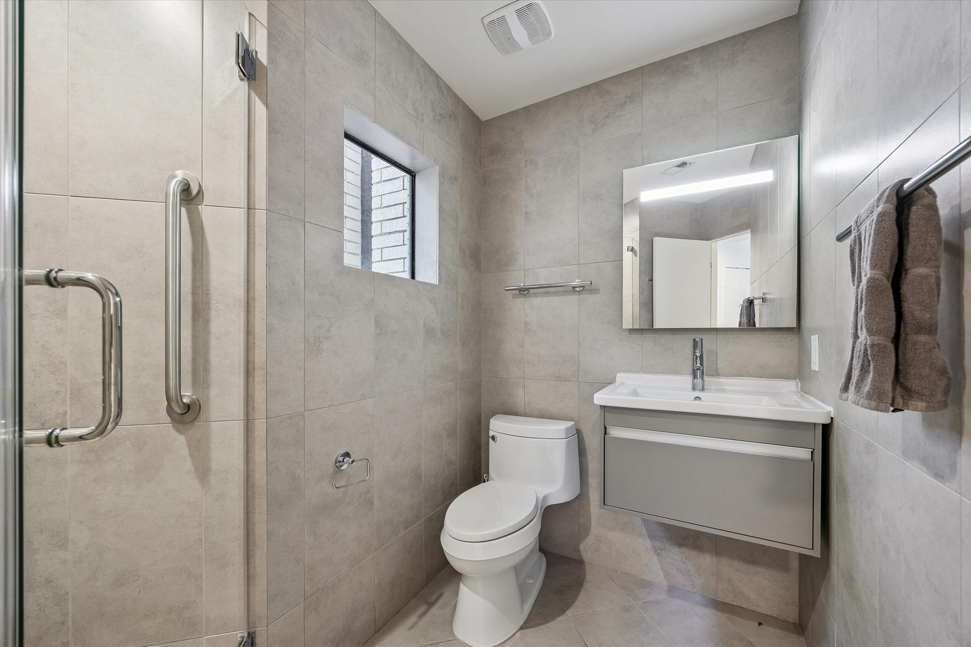 104 Gershwin Drive, Houston, TX 77079 Updated bath features modern floor-to-ceiling tile, a sleek vanity & glass-enclosed shower.