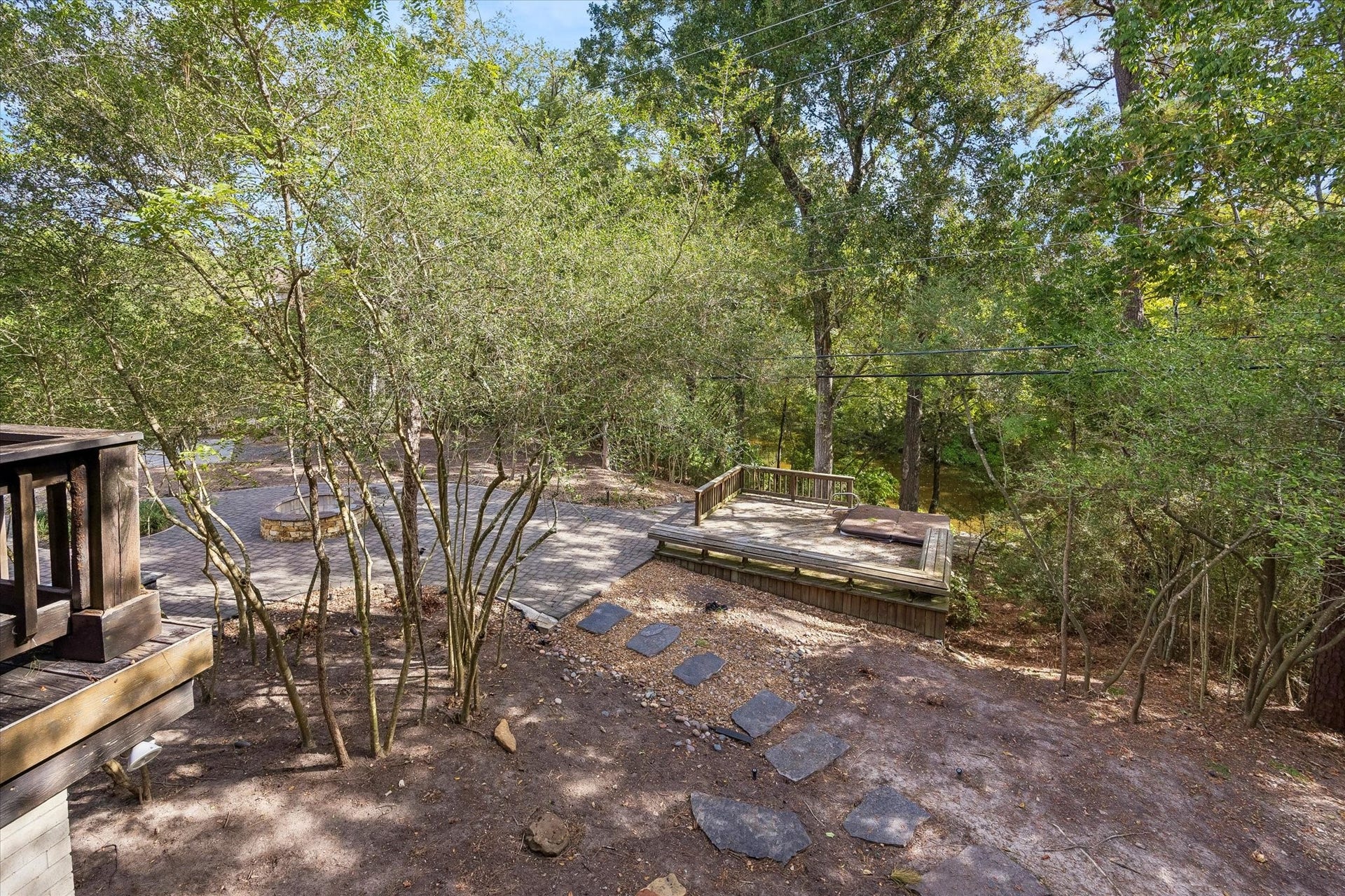 104 Gershwin Drive, Houston, TX 77079 View from the porch showcases the wonderful, wooded grounds below, w/stone pathways winding through the property & a hot tub/spa positioned to take advantage of the lake views beyond.