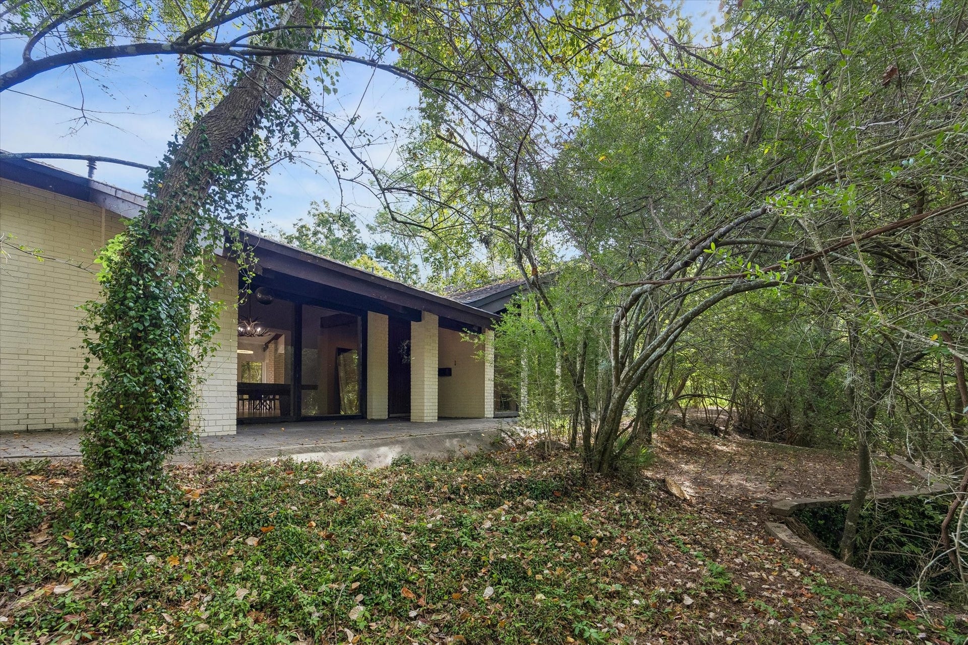 104 Gershwin Drive, Houston, TX 77079 Front exterior surrounded by lush woods along a scenic ravine, creating a beautiful natural setting w/lake access just beyond the property.