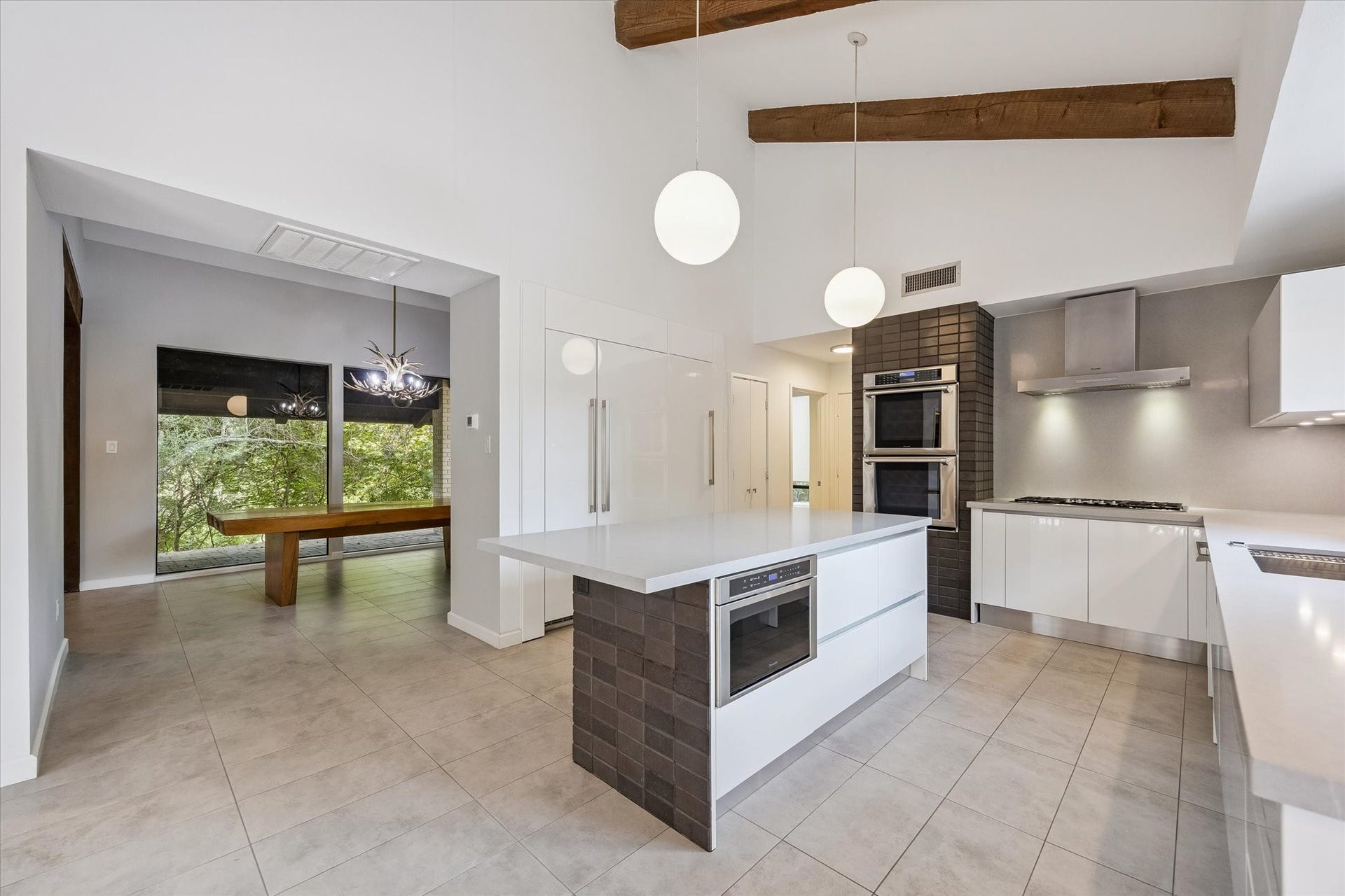 104 Gershwin Drive, Houston, TX 77079 Beautifully designed kitchen pairs sleek cabinetry w/warm architectural details, featuring a large center island w/breakfast bar seating, double ovens & statement pendant lighting beneath the vaulted beamed ceiling.
