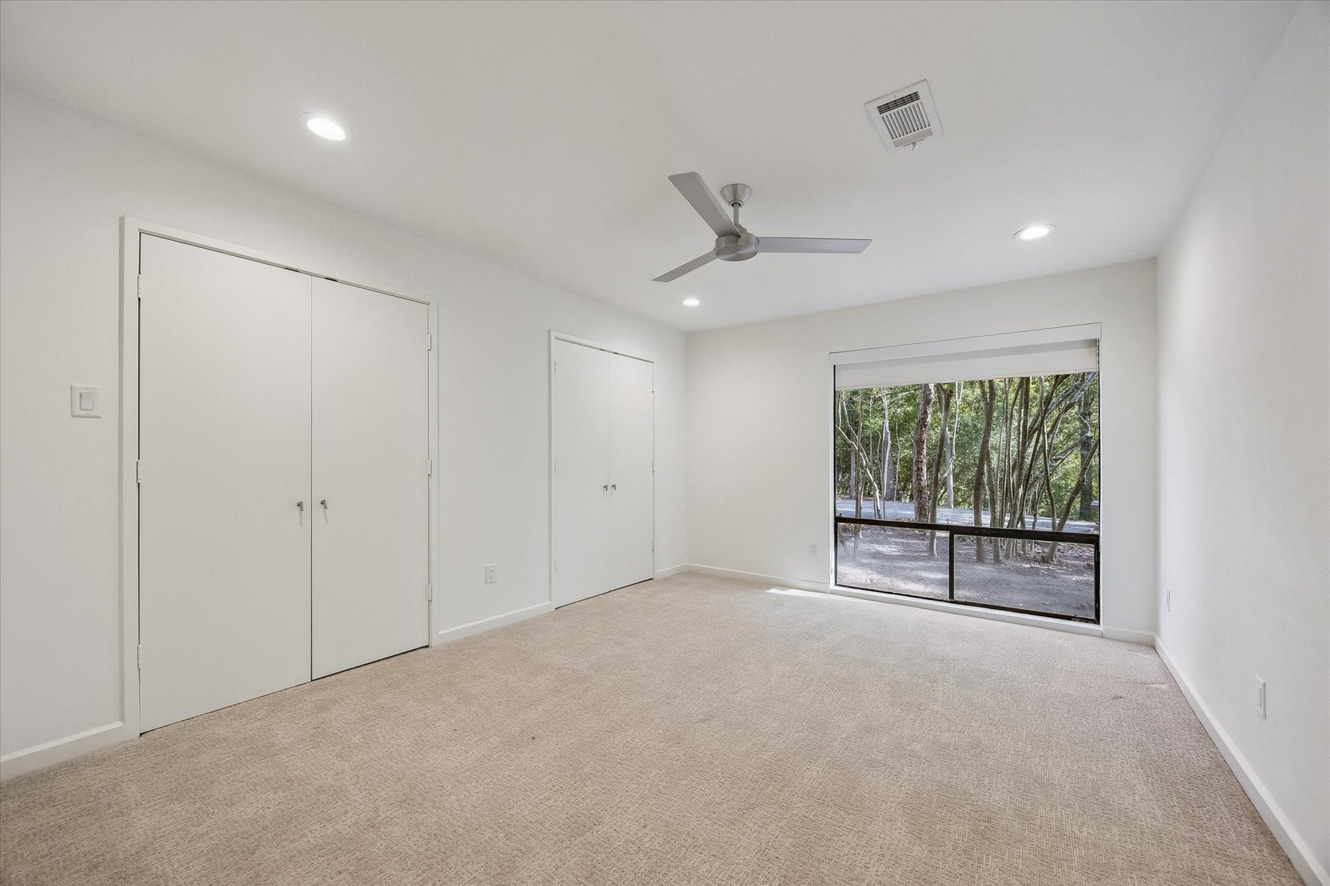 104 Gershwin Drive, Houston, TX 77079 Spacious secondary bedroom offers two closets, a ceiling fan & a large window providing natural light & views of the surrounding trees.