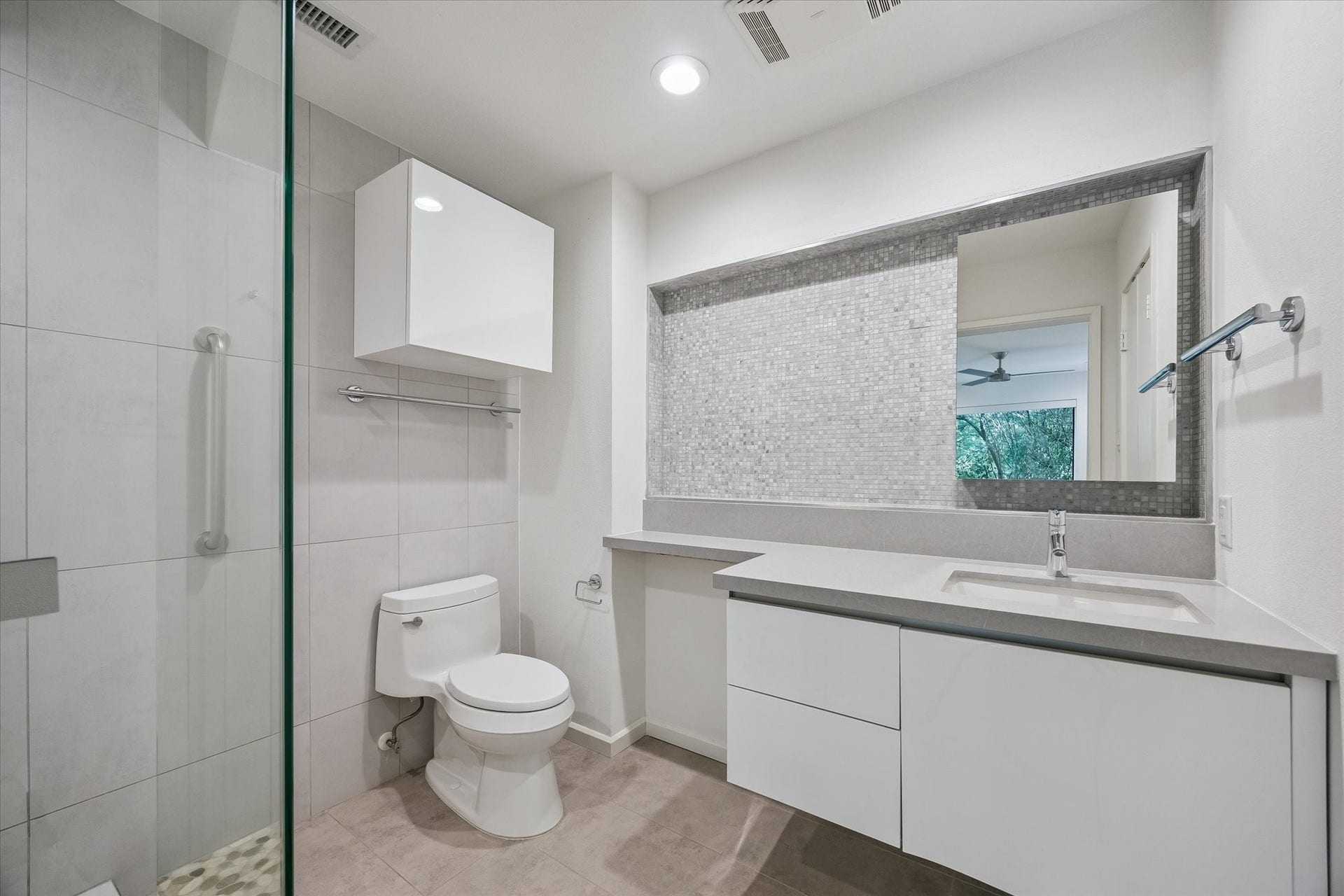104 Gershwin Drive, Houston, TX 77079 Updated secondary bath features a sleek vanity, modern fixtures & glass-enclosed, beautifully tiled shower.