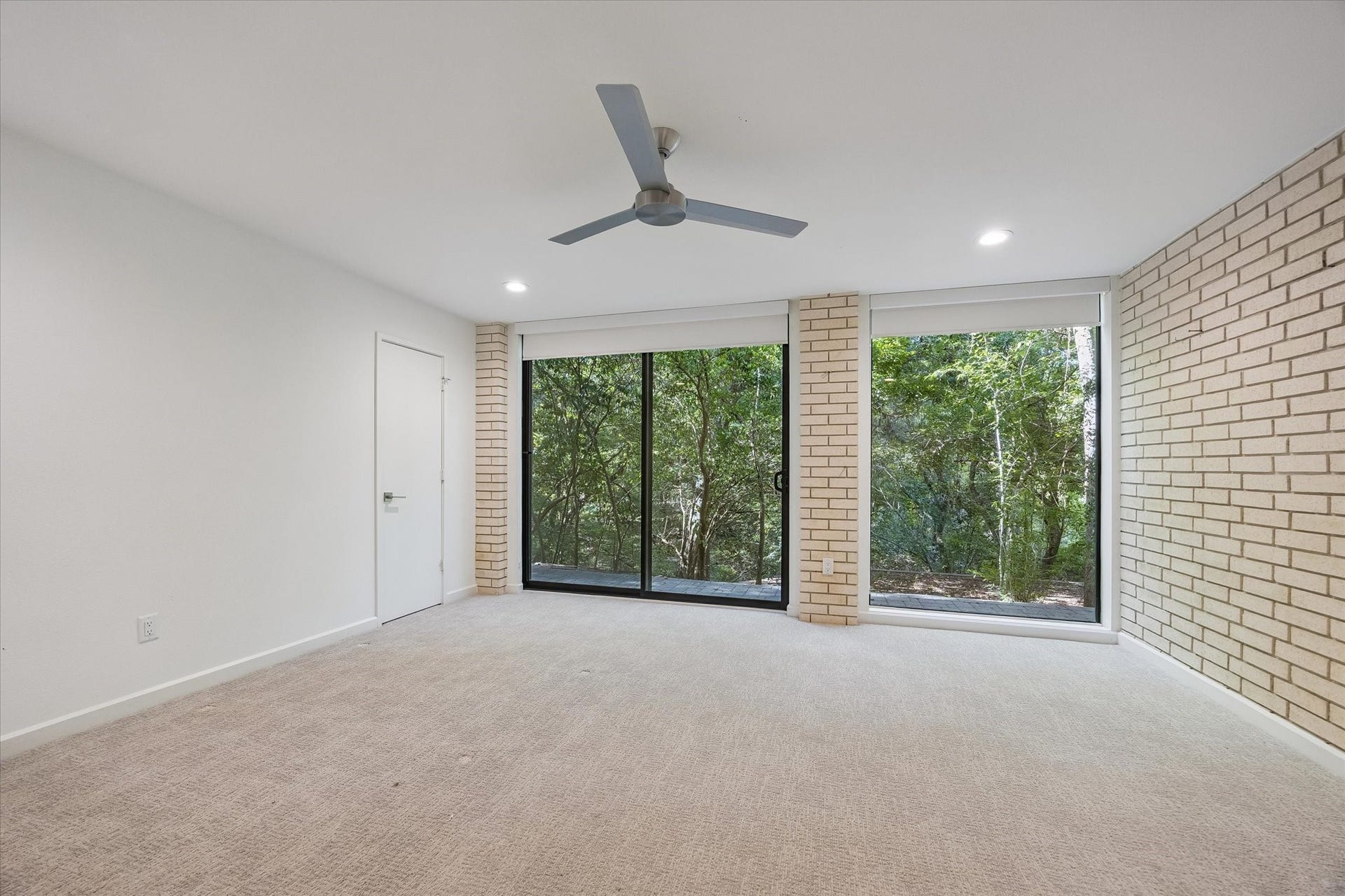 104 Gershwin Drive, Houston, TX 77079 Another view of this secondary bedroom features highlights the brick accent wall & large sliding glass doors that bring in natural light & provide direct outdoor access.
