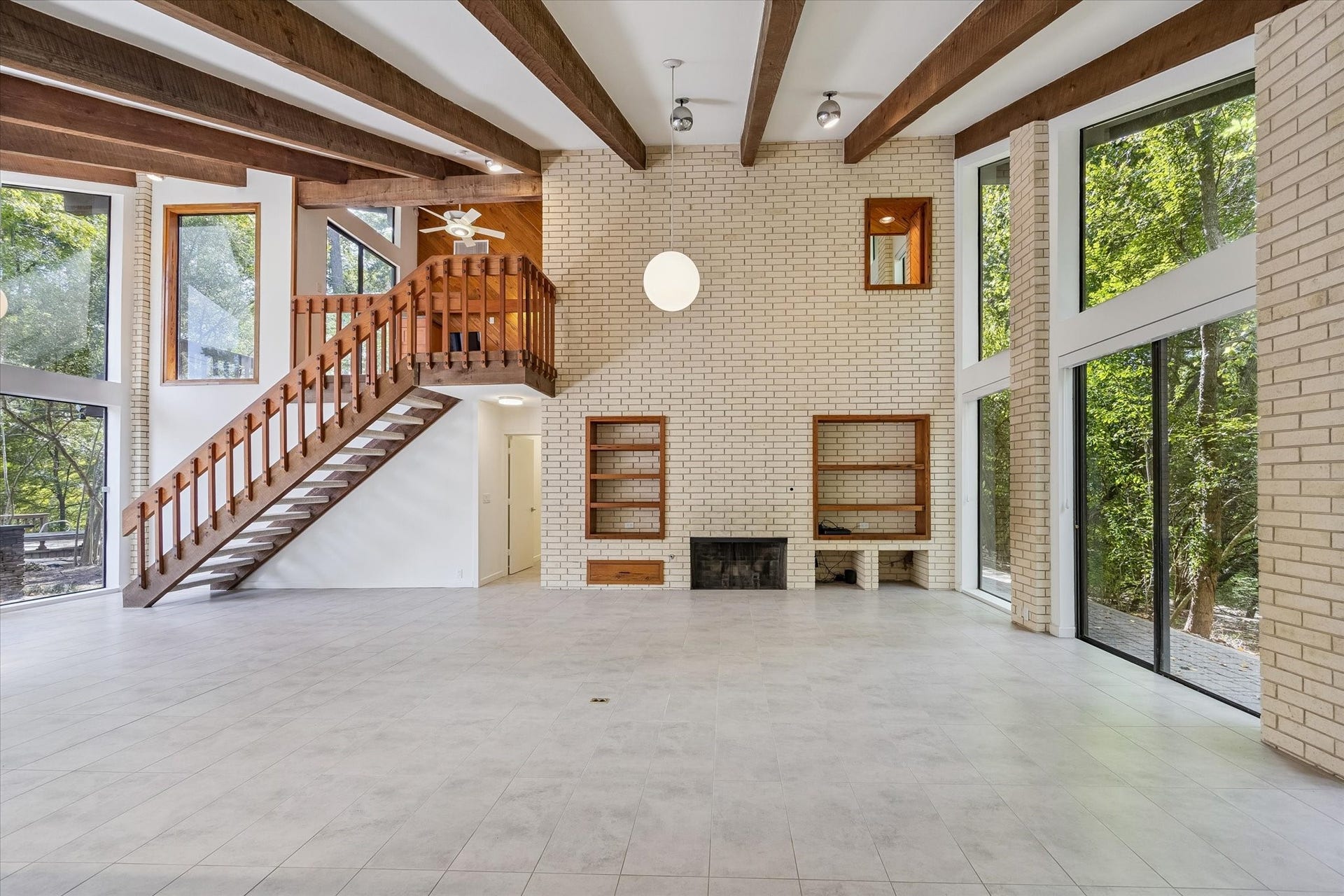 104 Gershwin Drive, Houston, TX 77079 The expansive living room makes an immediate impression w/a soaring beamed ceiling, brick fireplace, built-in shelving & an open staircase leading to the upper level.