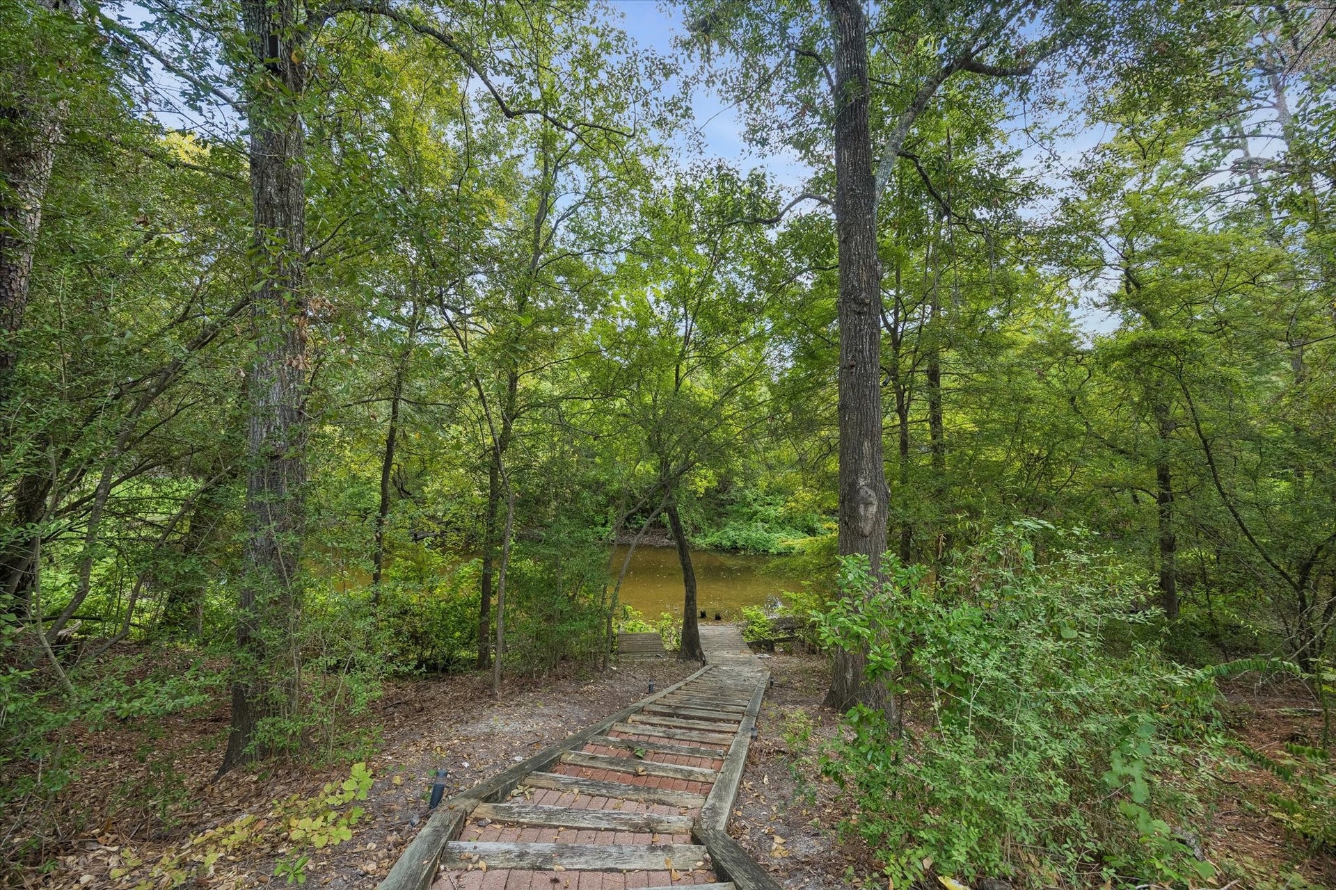 104 Gershwin Drive, Houston, TX 77079 Steps wind through the wooded grounds, creating a scenic pathway beneath the mature tree canopy leading directly to the lake.