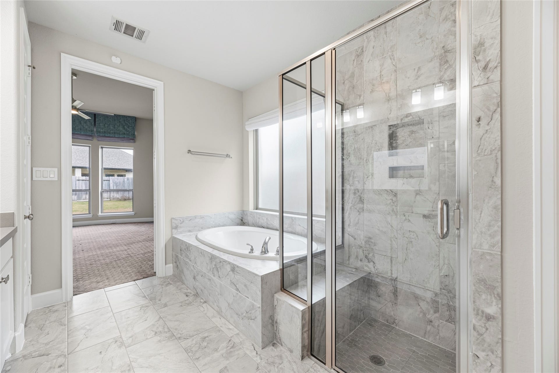 9511 Shaded Tree Drive, Missouri City, TX 77459 Primary en-suite with a double sink vanity, framed mirror, large walk-in shower and soaking tub.