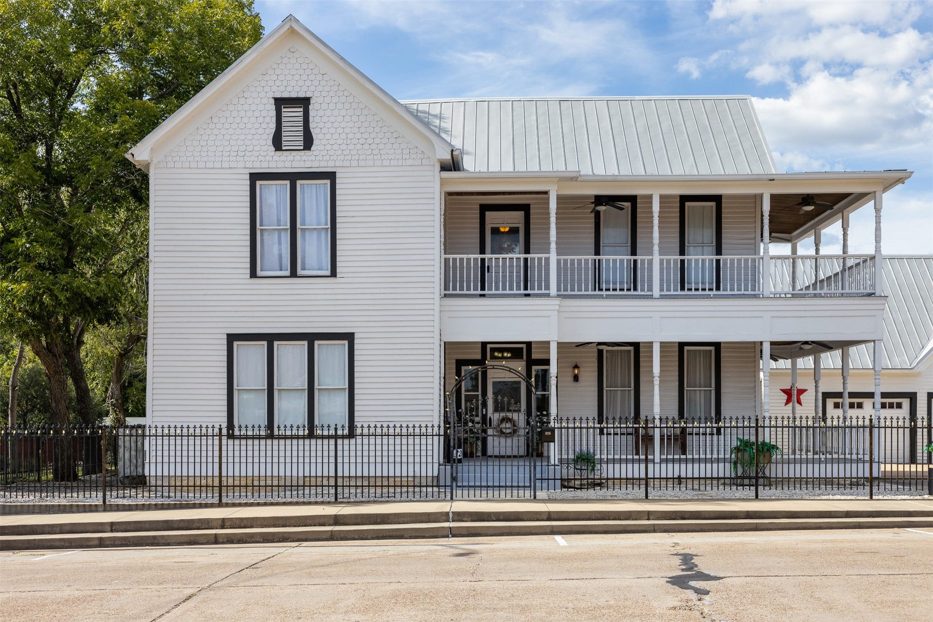 326 W Colorado Street, La Grange, TX 78945 Graceful double porches, classic black-and-white styling and a wrought-iron fence create an unforgettable first impression.
