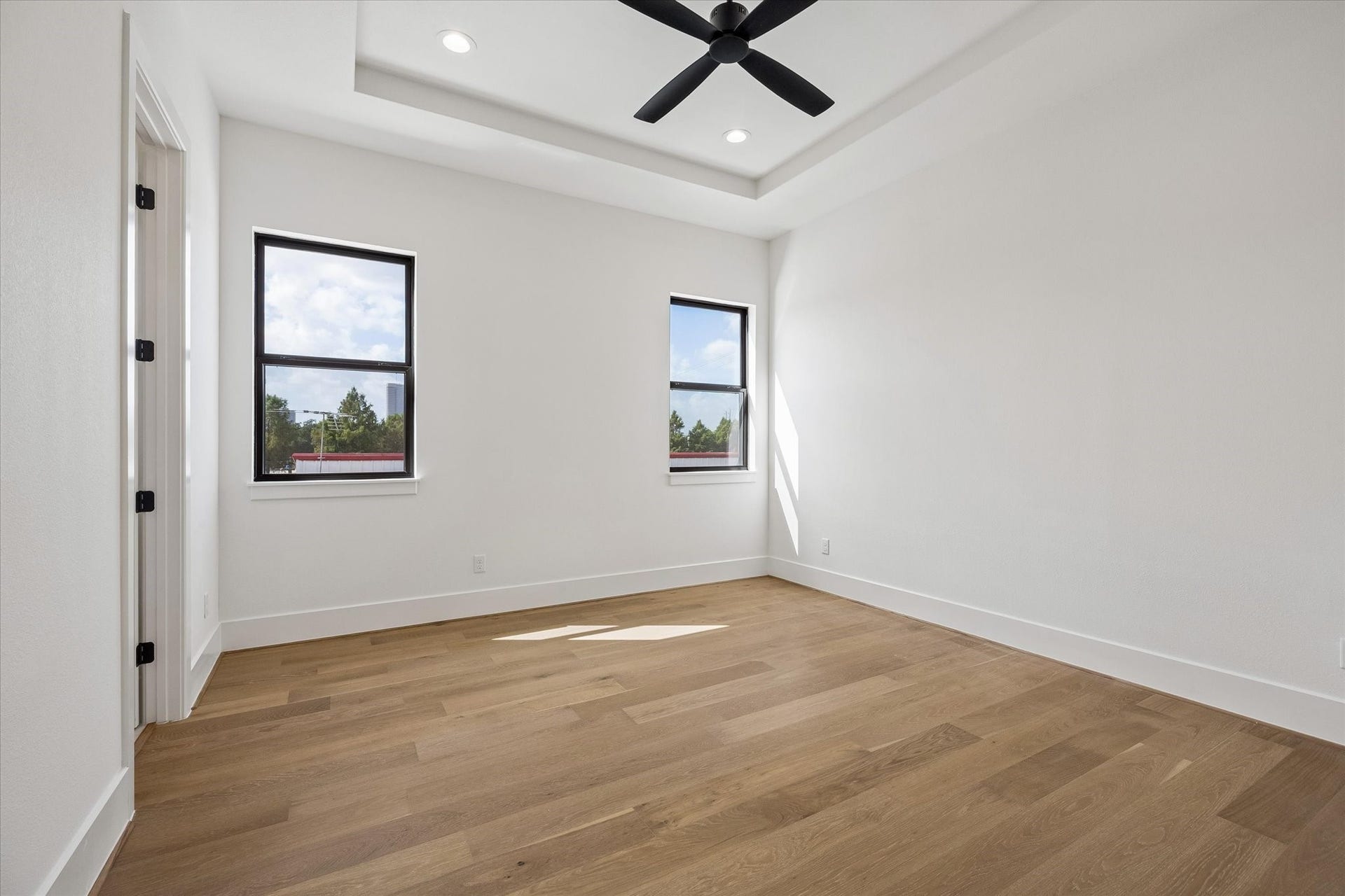 335 Harvard Street, Houston, TX 77007 Clean lines and a tray ceiling give this secondary bedroom a polished architectural feel, while two black framed windows bring in natural light and elevated neighborhood views.