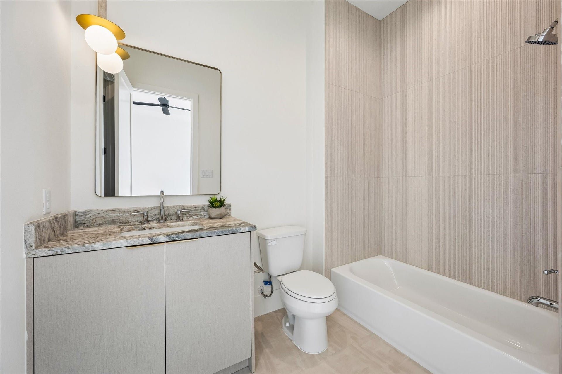 335 Harvard Street, Houston, TX 77007 Private ensuite bath complements the secondary bedroom with a stone topped vanity, streamlined cabinetry and full tub and shower combination wrapped in textured tile.
