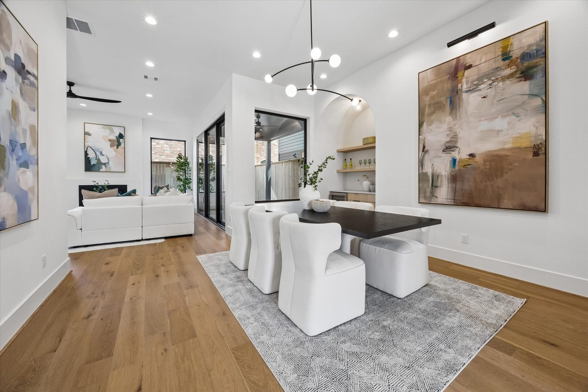 335 Harvard Street, Houston, TX 77007 Designed for effortless entertaining, the dining area sits between the main living spaces with a sculptural statement fixture overhead. An arched alcove with floating wood shelves and built in cabinetry creates a beautifully integrated serving and display area.