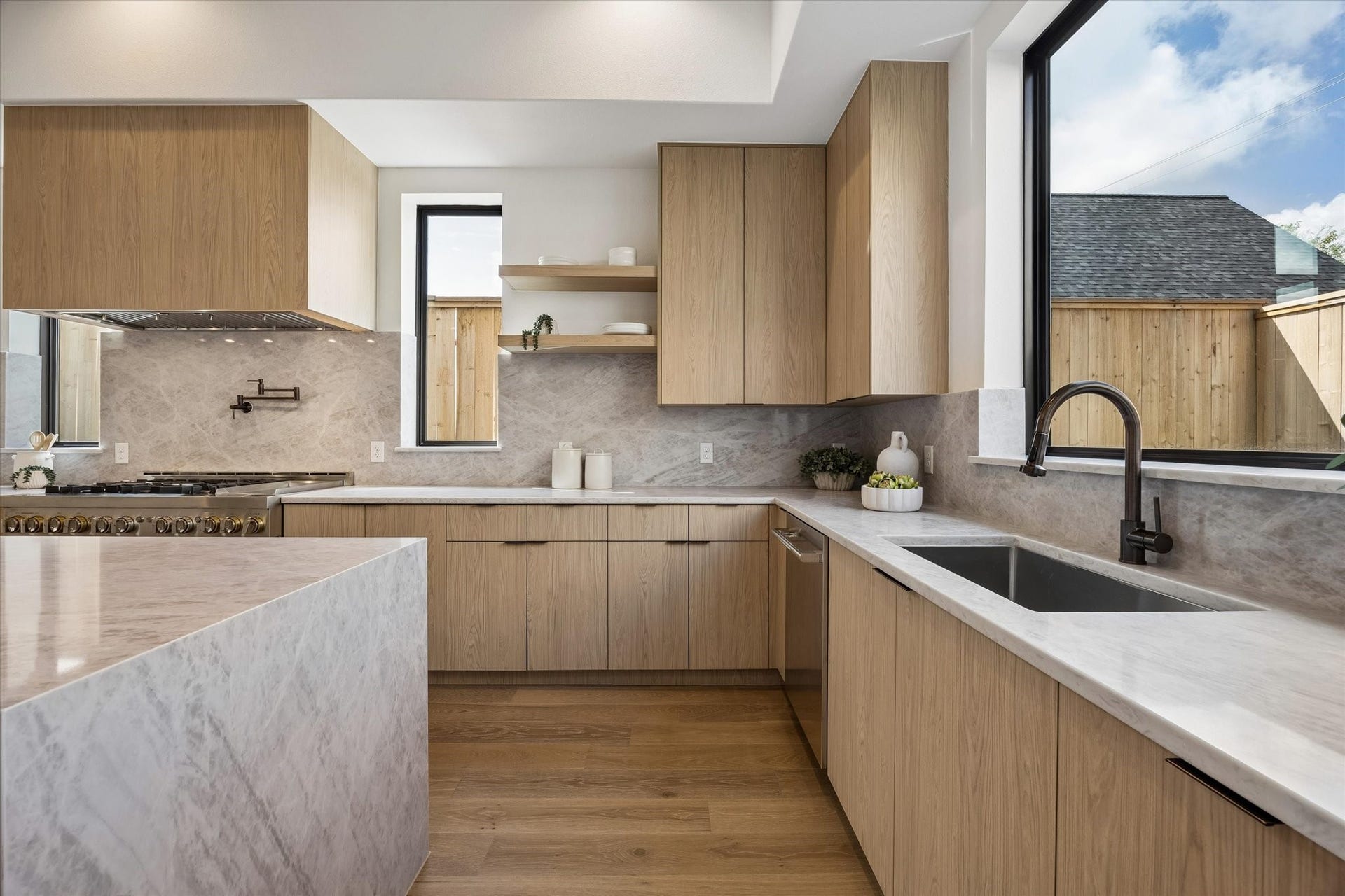 335 Harvard Street, Houston, TX 77007 Thoughtful cabinetry extends around the kitchen to maximize storage while maintaining the clean, minimalist aesthetic. Open shelving, an undermount sink and expansive picture window add warmth and natural light to the workspace.