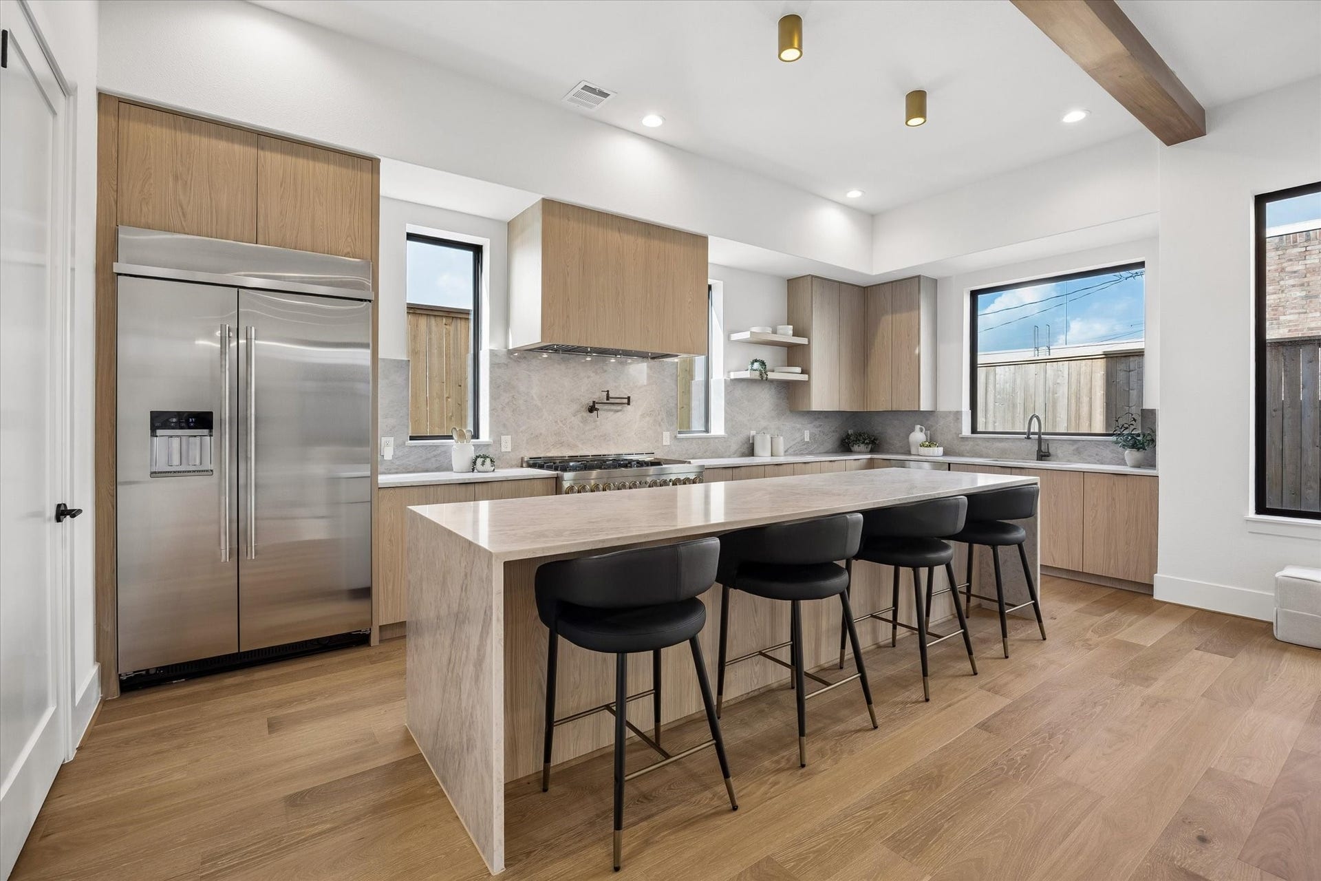 335 Harvard Street, Houston, TX 77007 Generous proportions make the kitchen equally suited to everyday meals and entertaining, with an oversized waterfall island, abundant cabinetry and professional style appliances. Warm wood tones and brass ceiling accents soften the clean, modern palette.