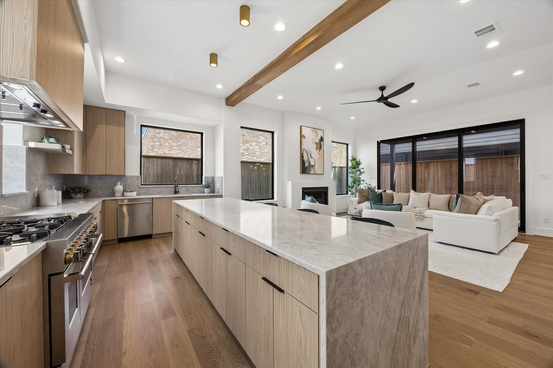 335 Harvard Street, Houston, TX 77007 Designed as the heart of the home, the kitchen opens directly to the living area while a substantial wood ceiling beam creates subtle architectural separation. Wide sightlines and oversized windows keep both spaces visually connected and filled with natural light.