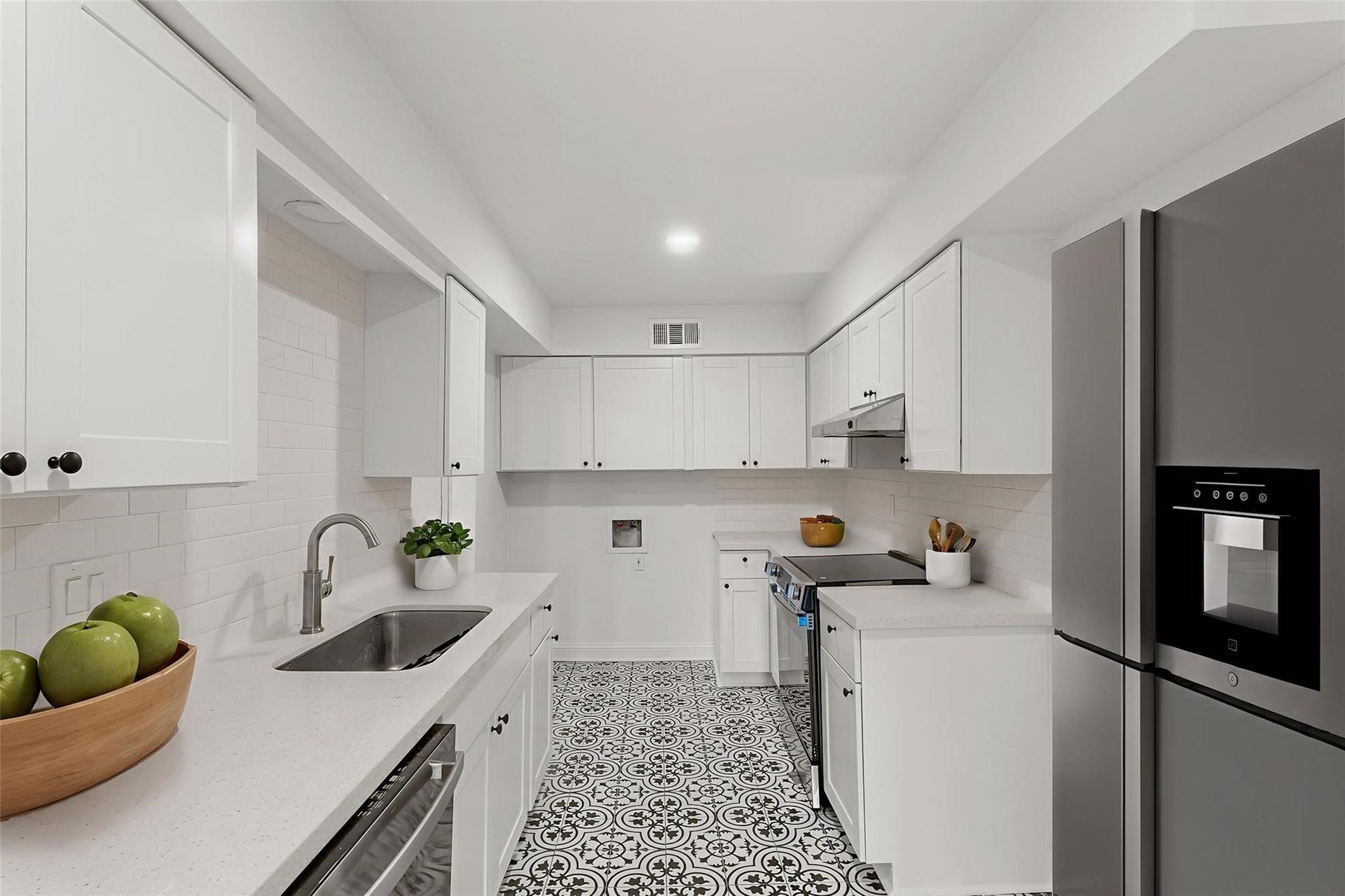 355 N Post Oak Lane, #839, Houston, TX 77024 Sleek and modern kitchen featuring white cabinetry, stylish patterned tile flooring, and stainless steel appliances for a contemporary touch.