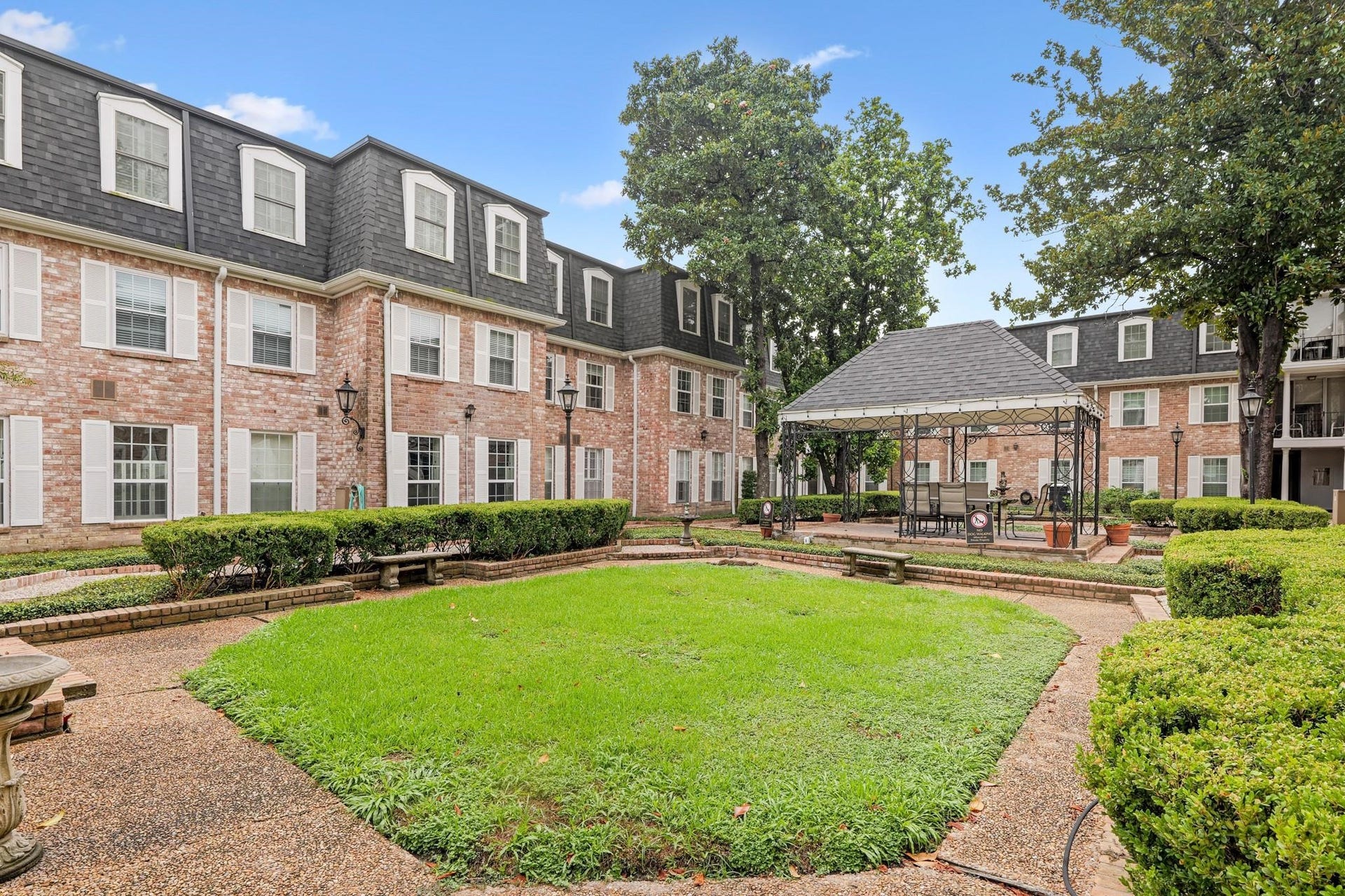 355 N Post Oak Lane, #839, Houston, TX 77024 Charming courtyard with lush greenery and a stylish gazebo, nestled between classic brick buildings for a serene outdoor retreat.