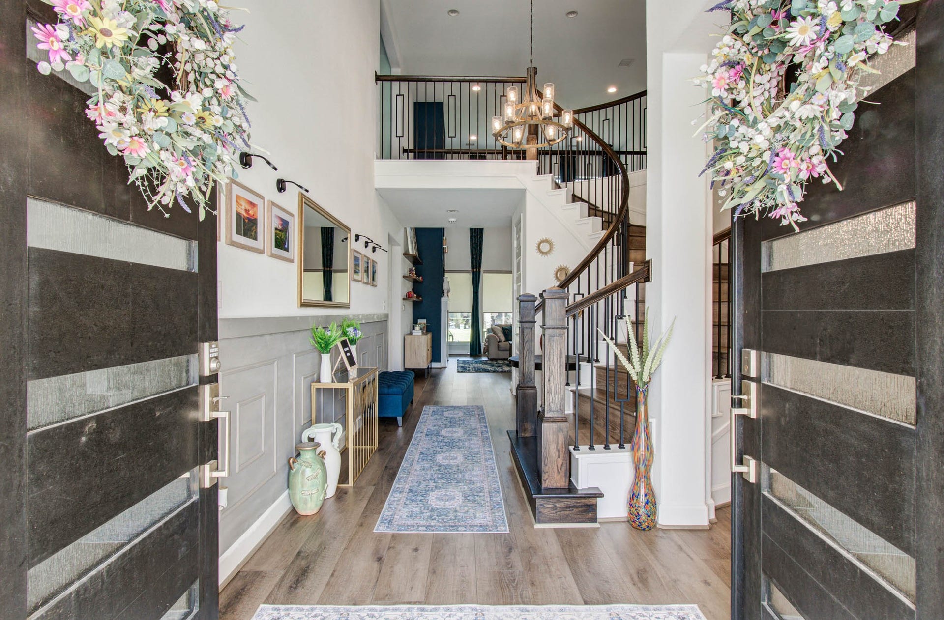 24430 Switchgrass Valley Way, Katy, TX 77493 Step into elegance through grand double doors with floral wreaths, revealing a bright foyer with wood flooring and a graceful curved staircase, all enhanced by stylish light fixtures and decorative touches for a sophisticated ambiance.