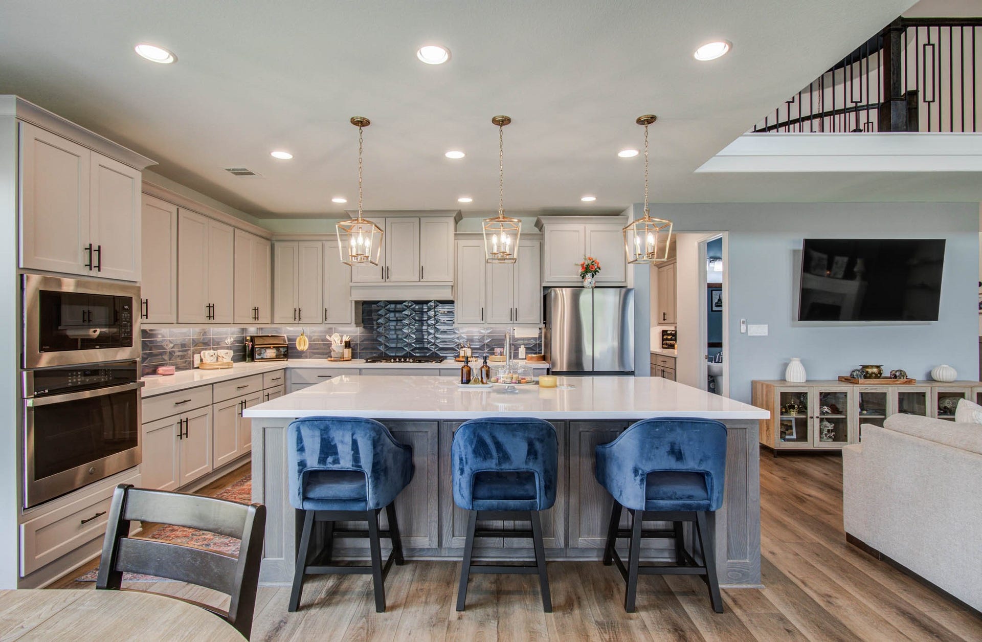 24430 Switchgrass Valley Way, Katy, TX 77493 Experience modern living in this open-concept kitchen featuring a spacious island with seating for three, seamlessly flowing into a cozy living area with a wall-mounted TV.