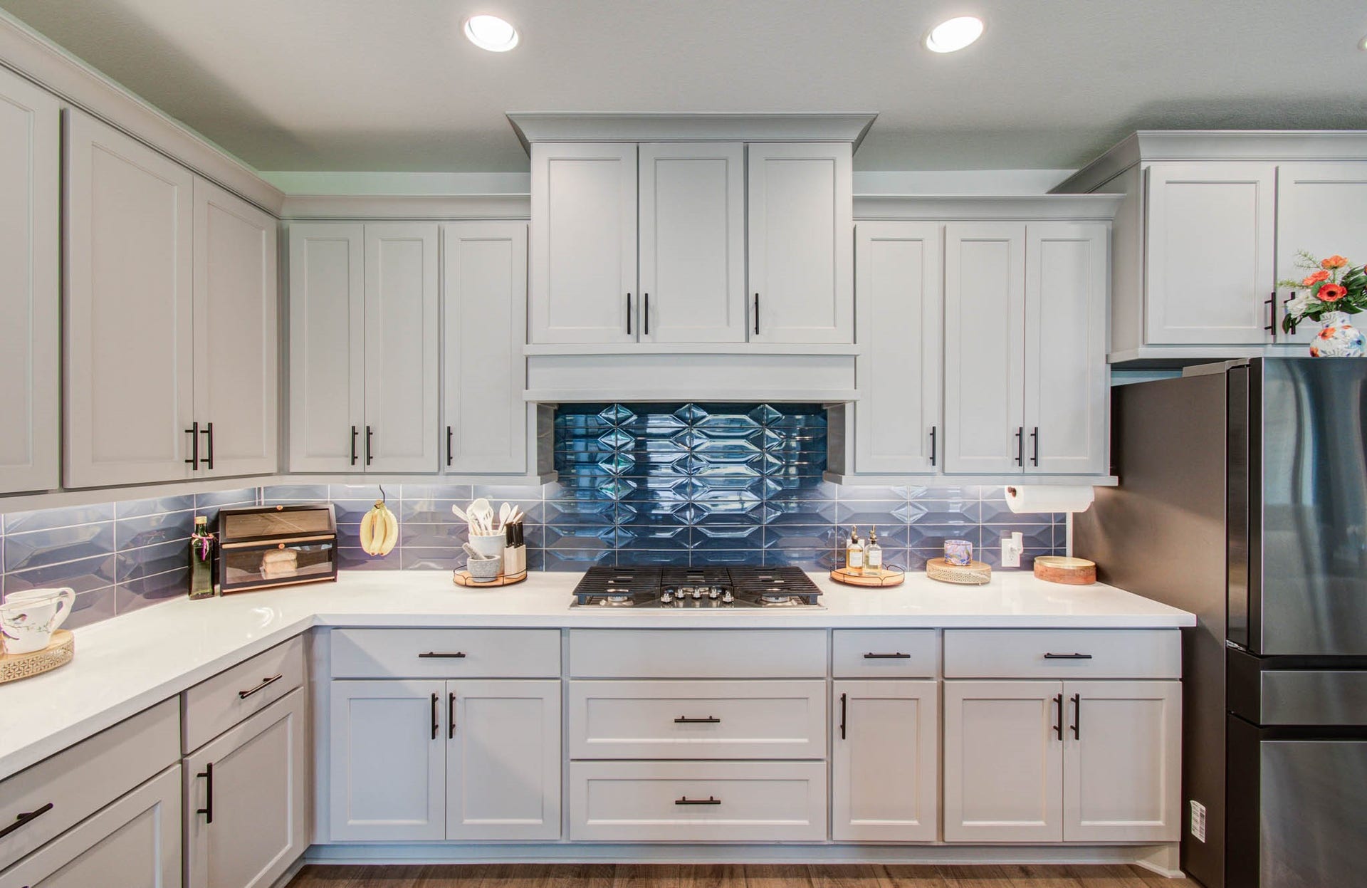 24430 Switchgrass Valley Way, Katy, TX 77493 This modern kitchen features sleek white cabinetry, a striking blue geometric tile backsplash, and stainless steel appliances. The space is well-lit with recessed lighting and offers ample counter space for cooking and entertaining.
