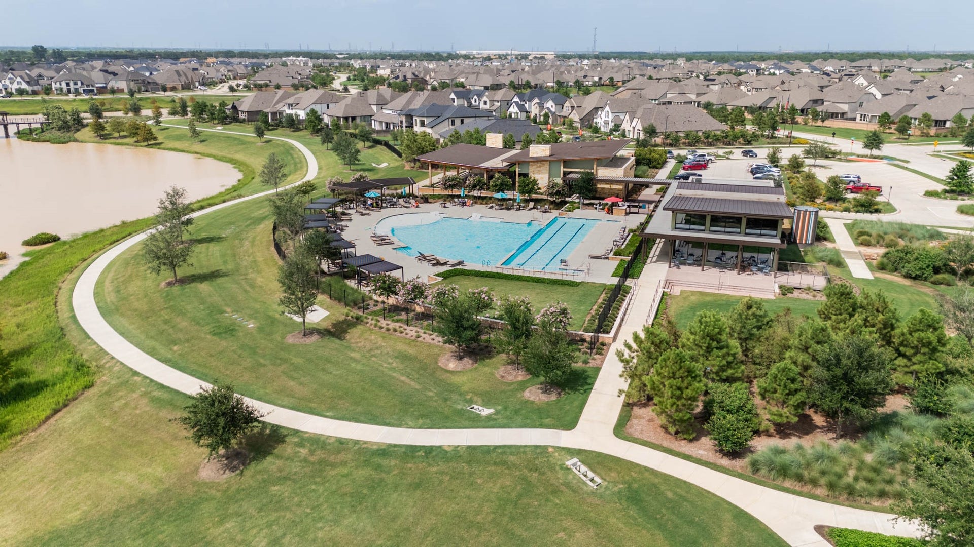24430 Switchgrass Valley Way, Katy, TX 77493 This photo showcases a vibrant community with a spacious outdoor recreational area featuring a large swimming pool, green spaces, and a scenic pond. The neighborhood is composed of modern, well-maintained homes, offering a tranquil yet active lifestyle.