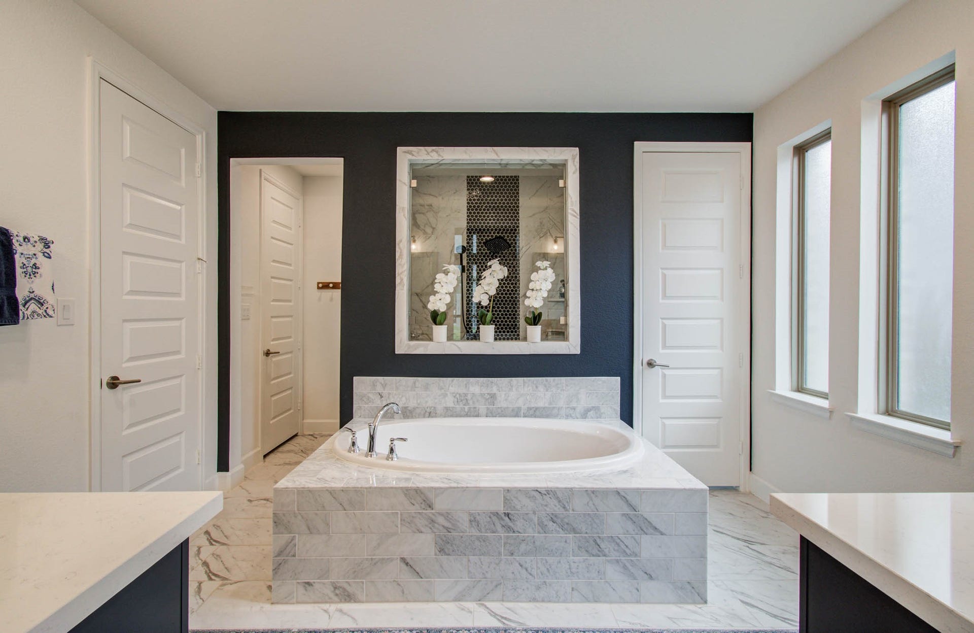 24430 Switchgrass Valley Way, Katy, TX 77493 A luxurious marble tub takes center stage against a striking dark accent wall, enhanced by abundant natural light from large windows, creating a spacious and elegant modern bathroom.
