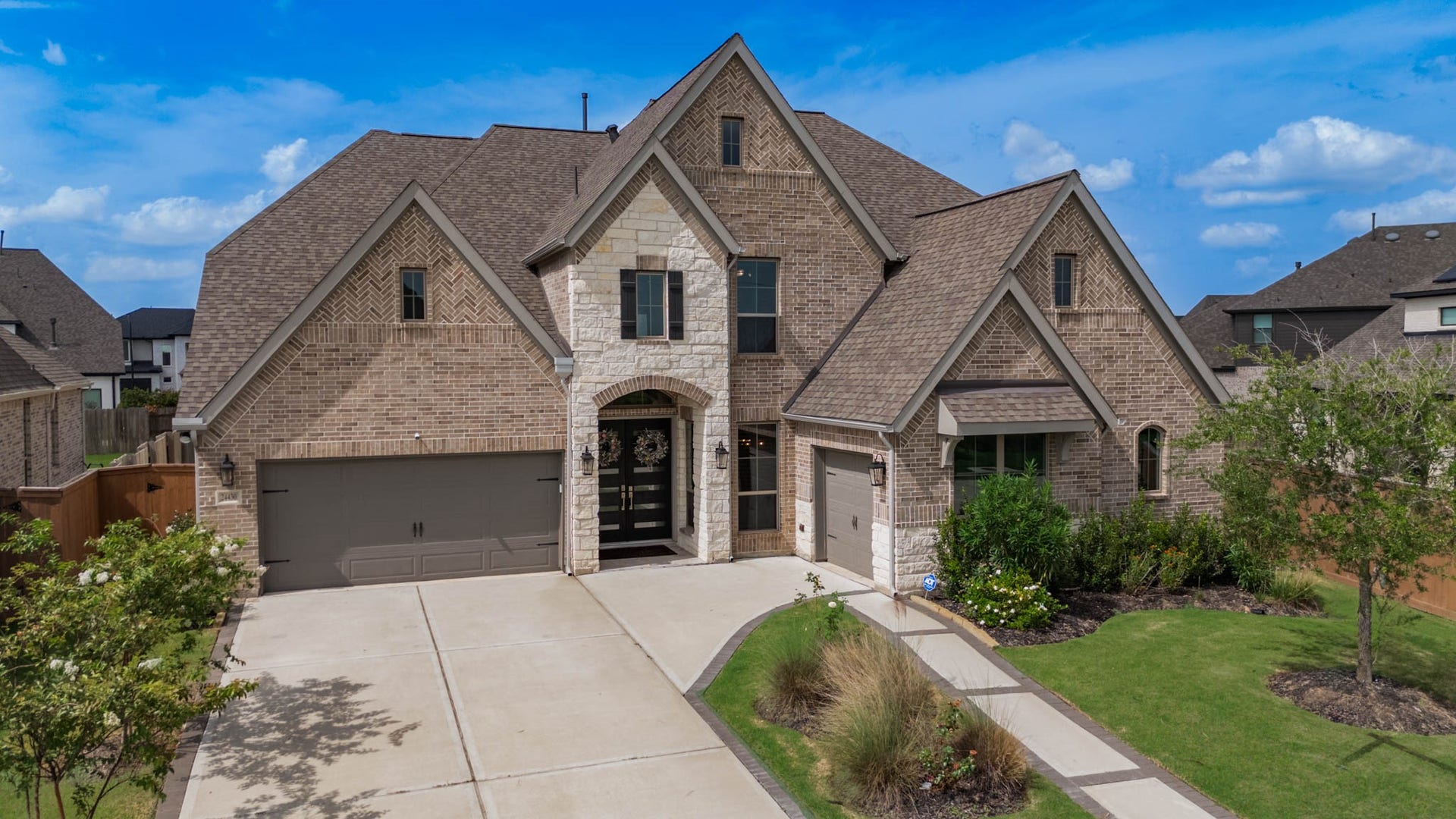 24430 Switchgrass Valley Way, Katy, TX 77493 Charming two-story brick home with modern design, featuring a spacious driveway, two-car garage, and well-maintained landscaping, all highlighted by an inviting stone and brick entryway.