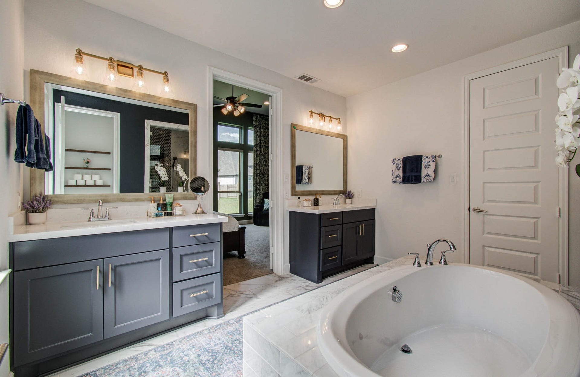 24430 Switchgrass Valley Way, Katy, TX 77493 This spacious bathroom features dual vanities with modern fixtures, a large soaking tub, and elegant lighting. Neutral tones and a glimpse into an adjoining room create a serene, cohesive atmosphere.