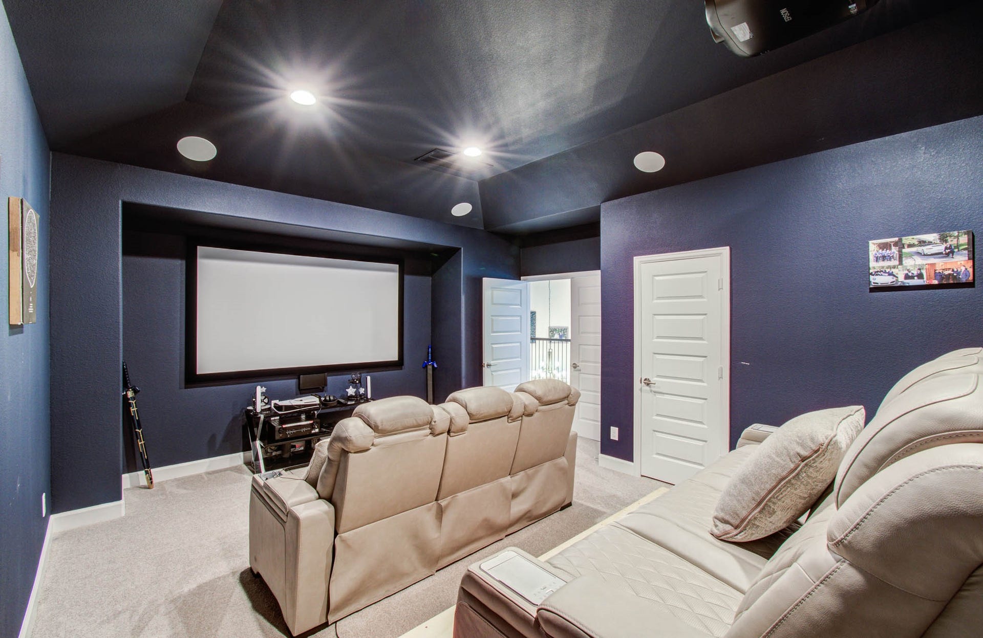 24430 Switchgrass Valley Way, Katy, TX 77493 Experience ultimate movie nights in this cozy, soundproof home theater with navy blue walls, featuring plush leather seating, a built-in projector, and a mounted screen, all illuminated by sleek ceiling lights.