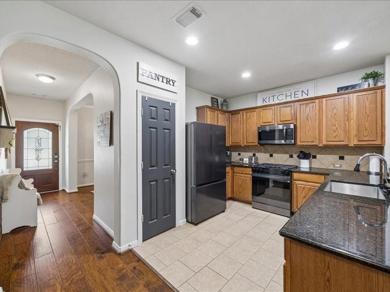 Open kitchen with granite countertops, gas cooking and stainless-steel appliances.