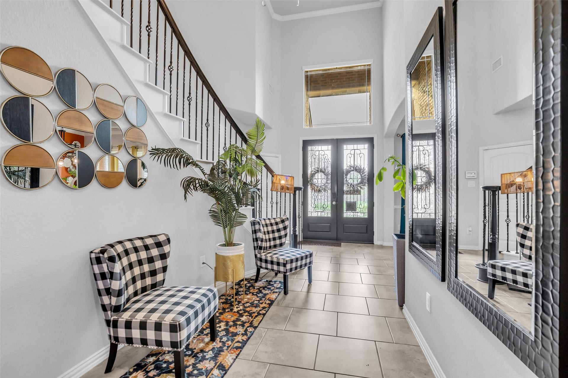 This elegant entryway features high ceilings, a staircase with decorative railing creating a welcoming and sophisticated entry ambiance.