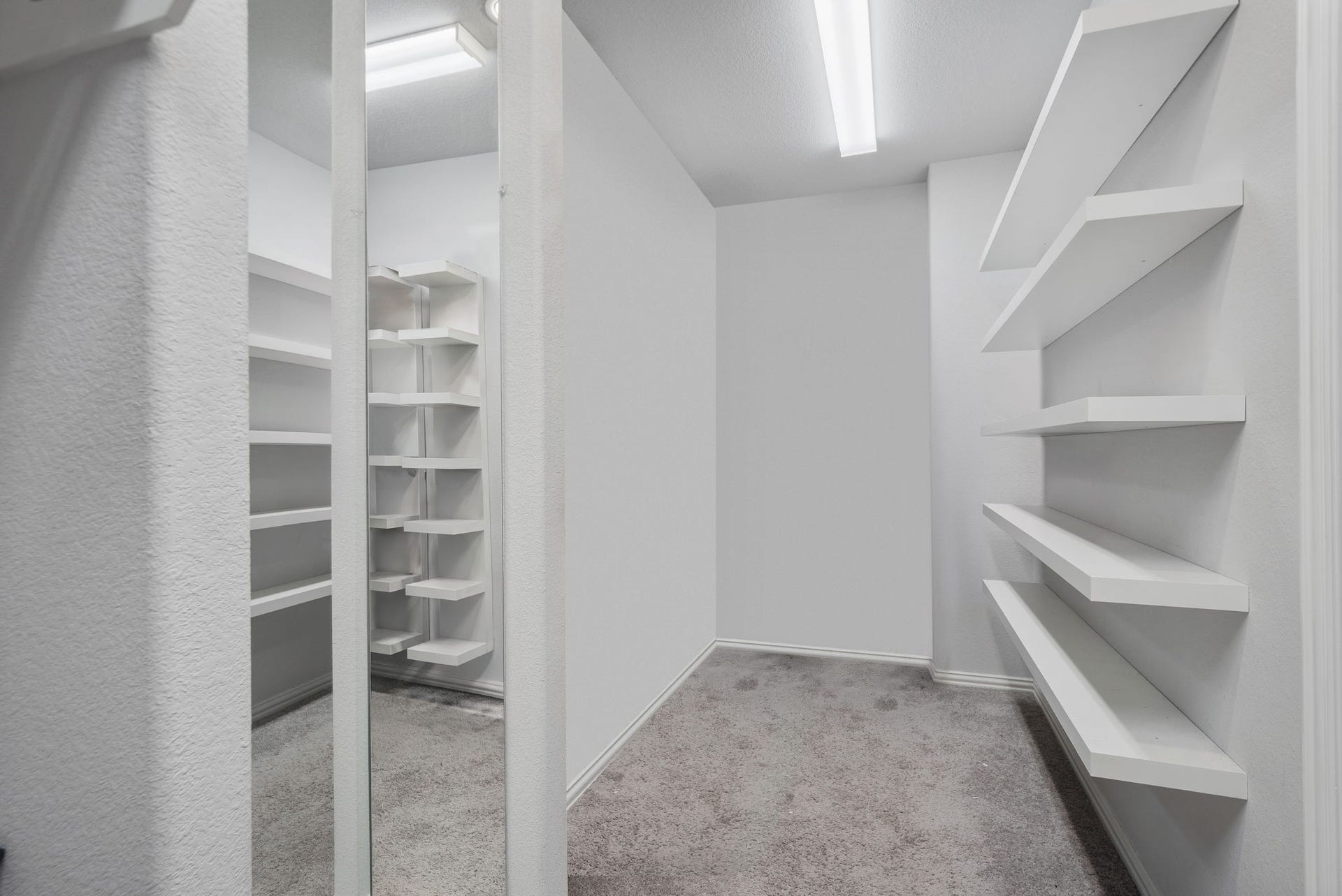 Primary walk-in spacious closet with custom shelves and mirrors.