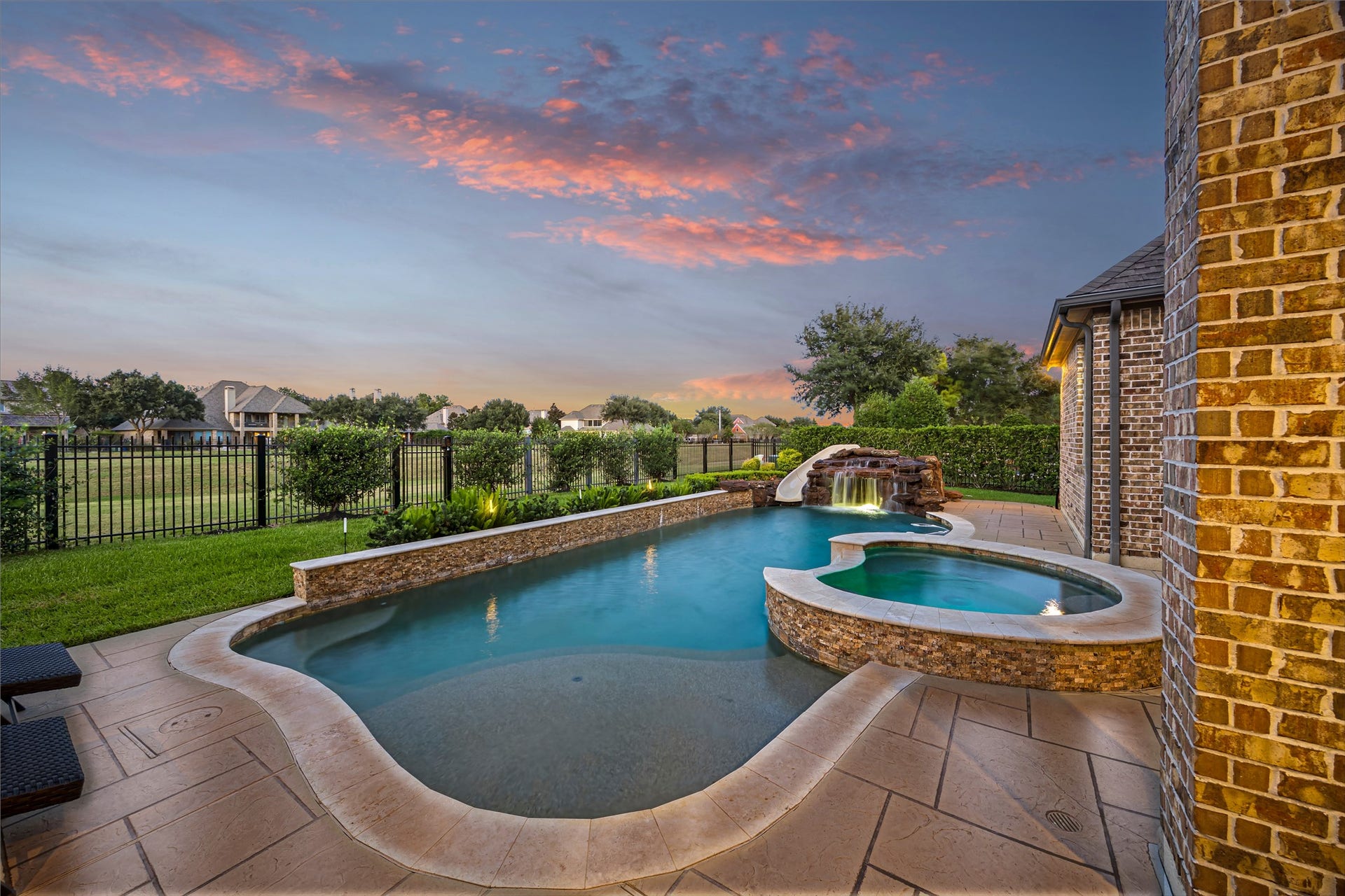 8642 Chickasaw Plum Way, Katy, TX 77494 Pool and spa glowing at twilight against the backyard landscape. Heated PebbleTec chlorine pool.