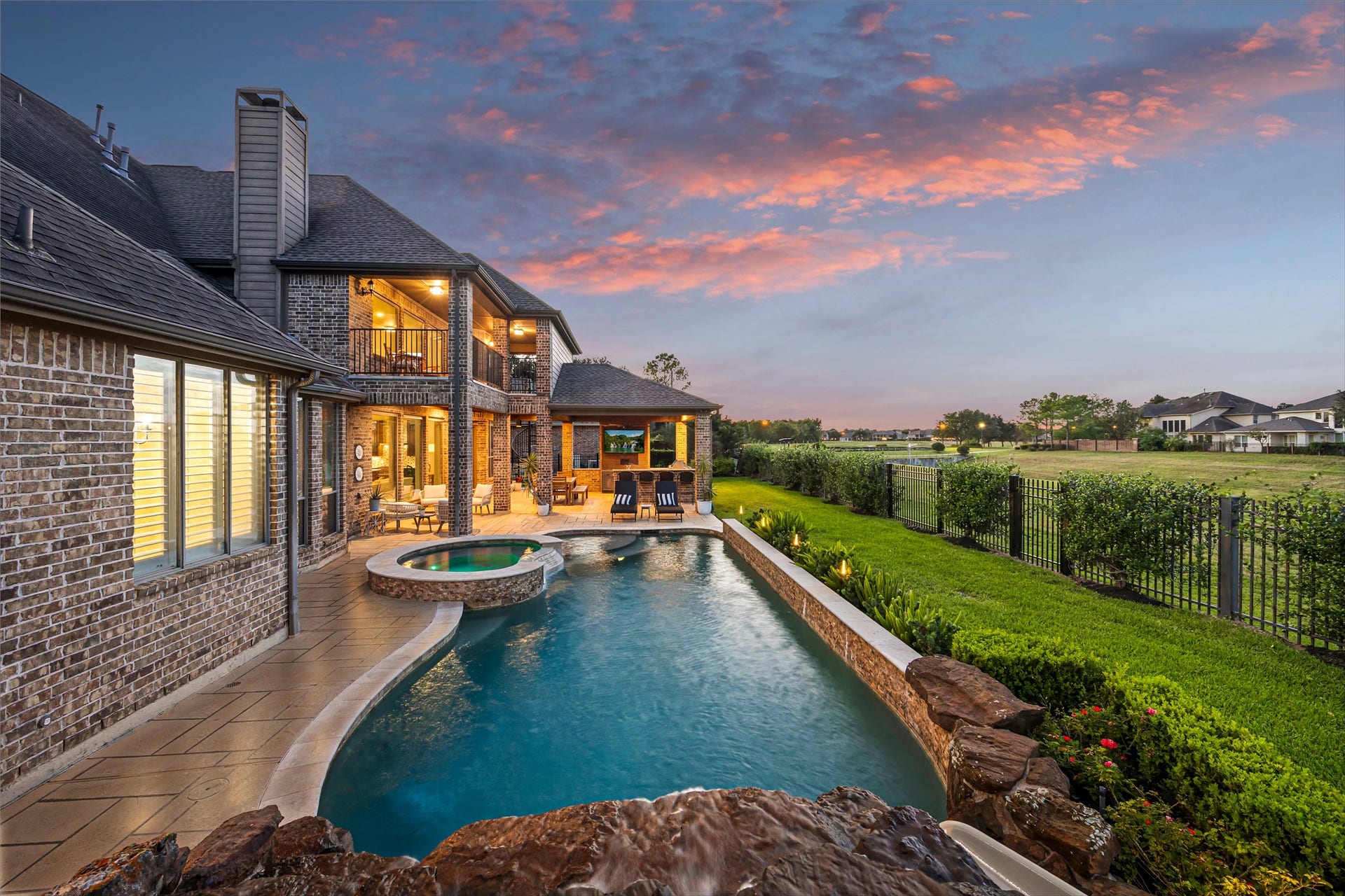 8642 Chickasaw Plum Way, Katy, TX 77494 Rear elevation with illuminated pool and spa at dusk. Heated PebbleTec chlorine pool.