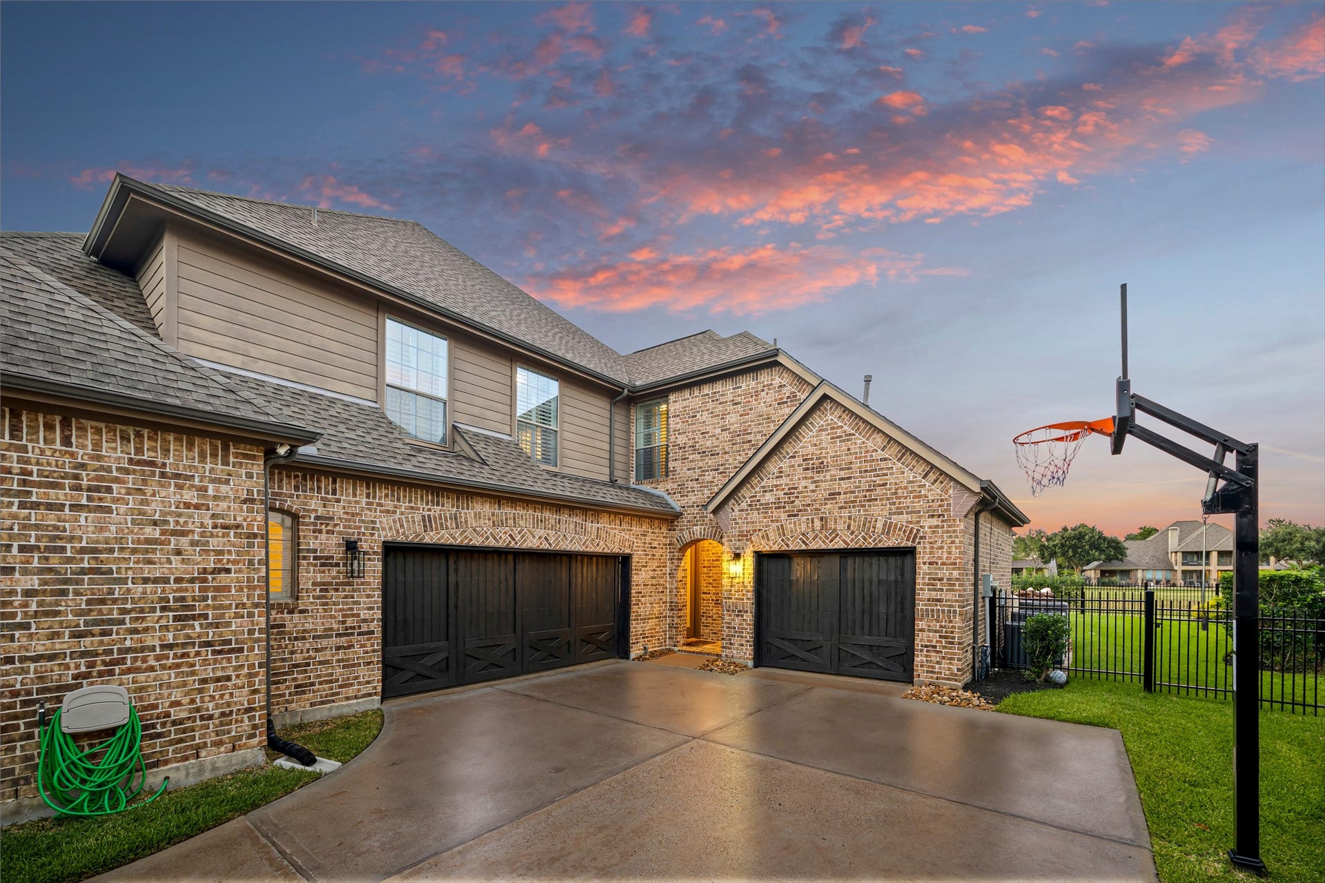 8642 Chickasaw Plum Way, Katy, TX 77494 Attached three car garage with wide driveway and refined brick and stone detailing. New windows (2024). (Virtually enhanced: driveway reflection)