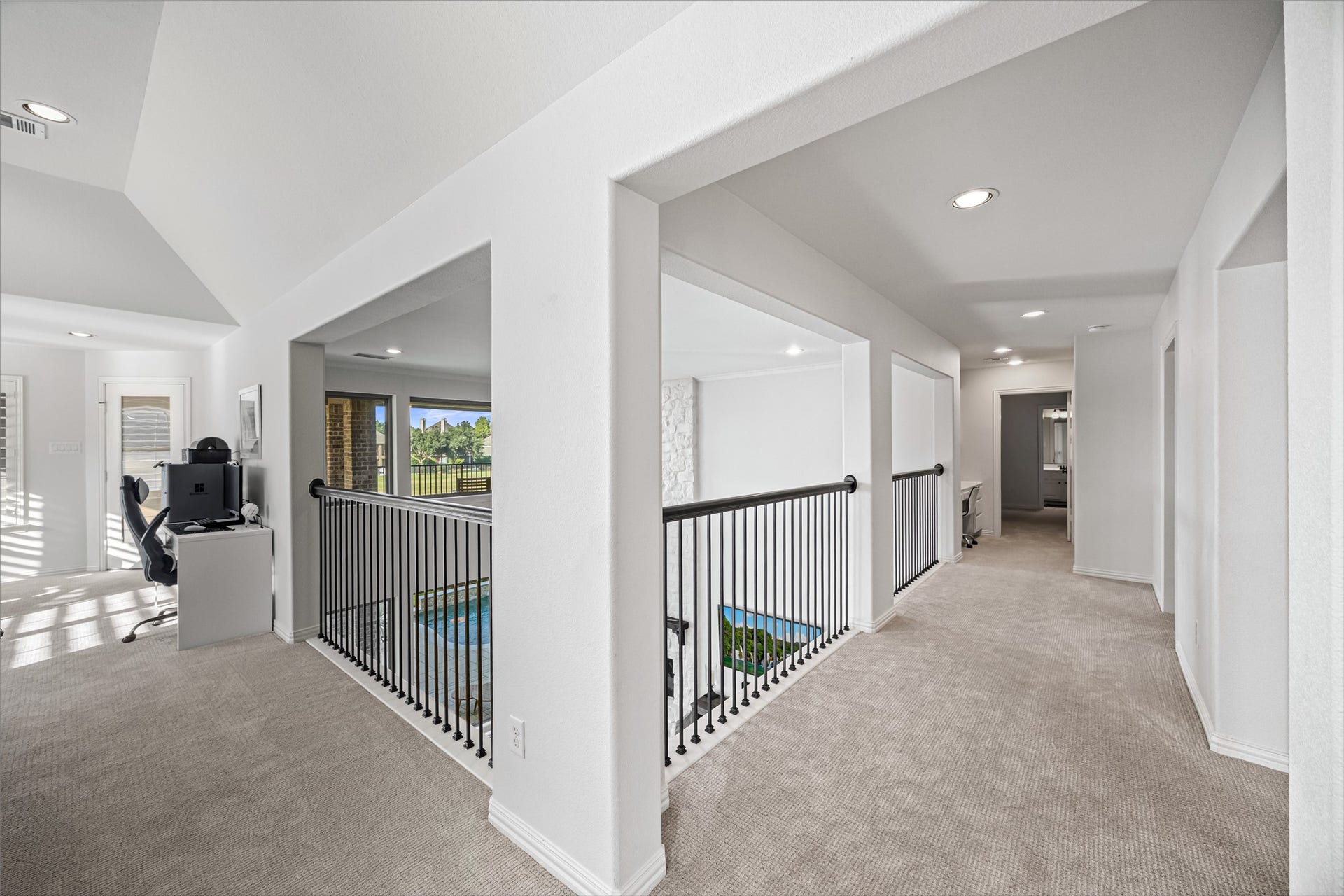 8642 Chickasaw Plum Way, Katy, TX 77494 Upstairs landing with wrought-iron railing overlooking the main level, recessed lighting, and plush carpet, connecting to the secondary bedrooms and a built-in office nook.