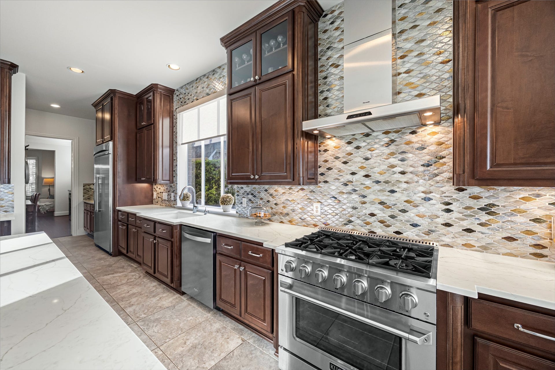 8642 Chickasaw Plum Way, Katy, TX 77494 Chef's kitchen with mosaic tile backsplash, professional-style stainless steel range, and dark wood cabinetry. New luxury Kucht professional stove and oven (2024). New quartz countertops and backsplash (2024).