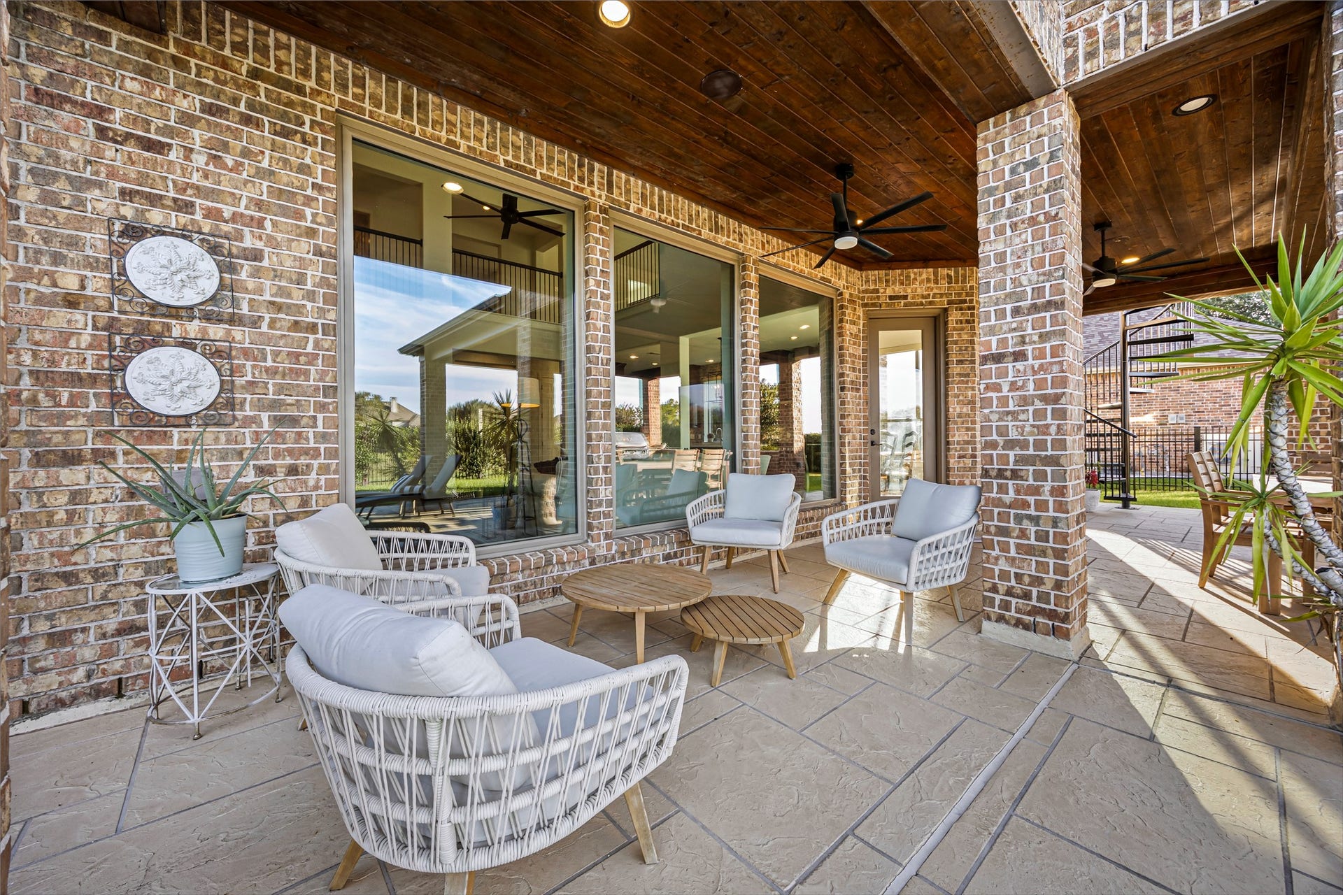 8642 Chickasaw Plum Way, Katy, TX 77494 Covered patio lounge with stone accents and seating area overlooking the grounds. Exterior surround sound and ceiling fans.