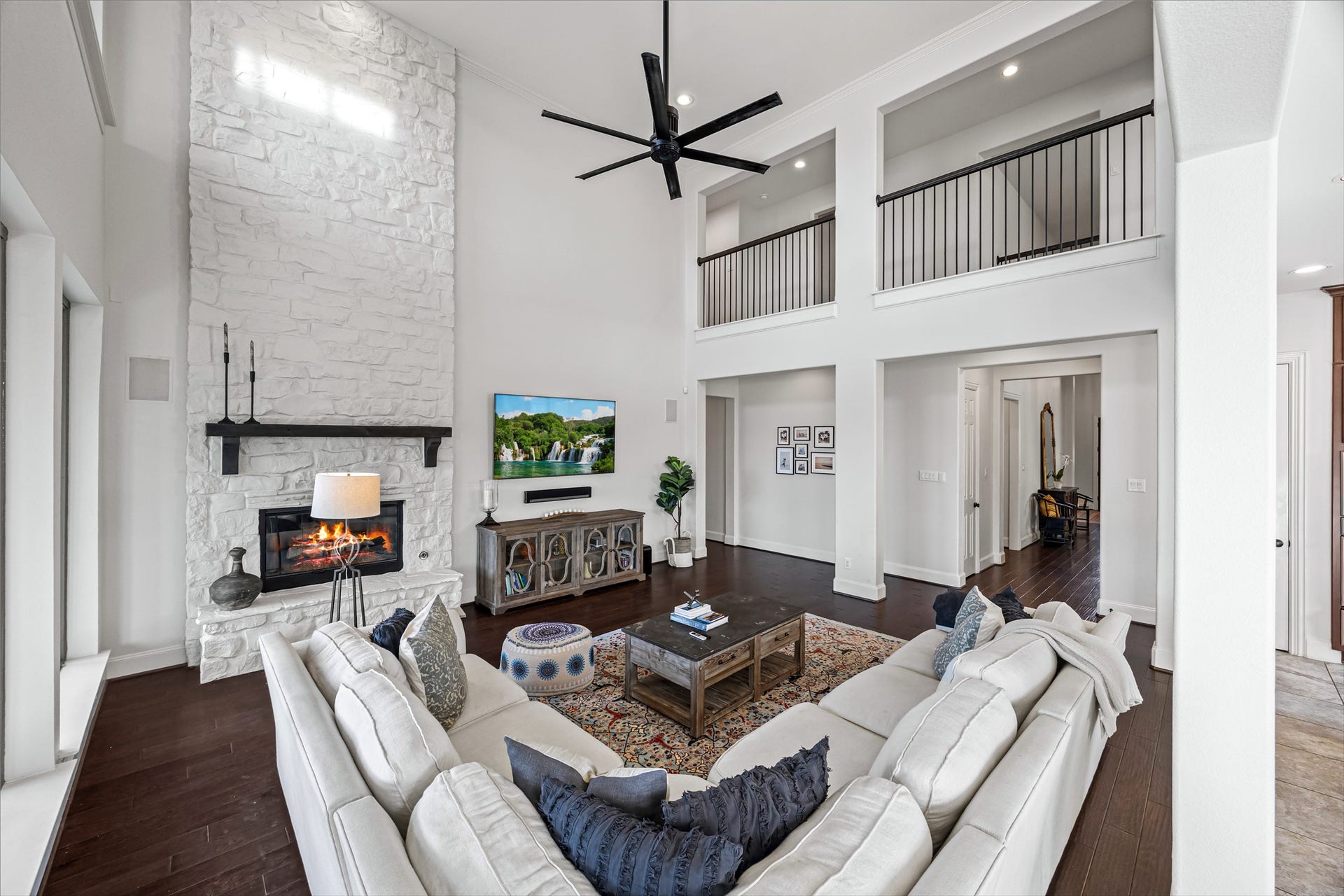 8642 Chickasaw Plum Way, Katy, TX 77494 Expansive living room with high ceilings, ceiling fan, and an open, airy layout. Painted fireplace with updated stone, built-in speakers, and Big Ass Fan controlled by Nest.