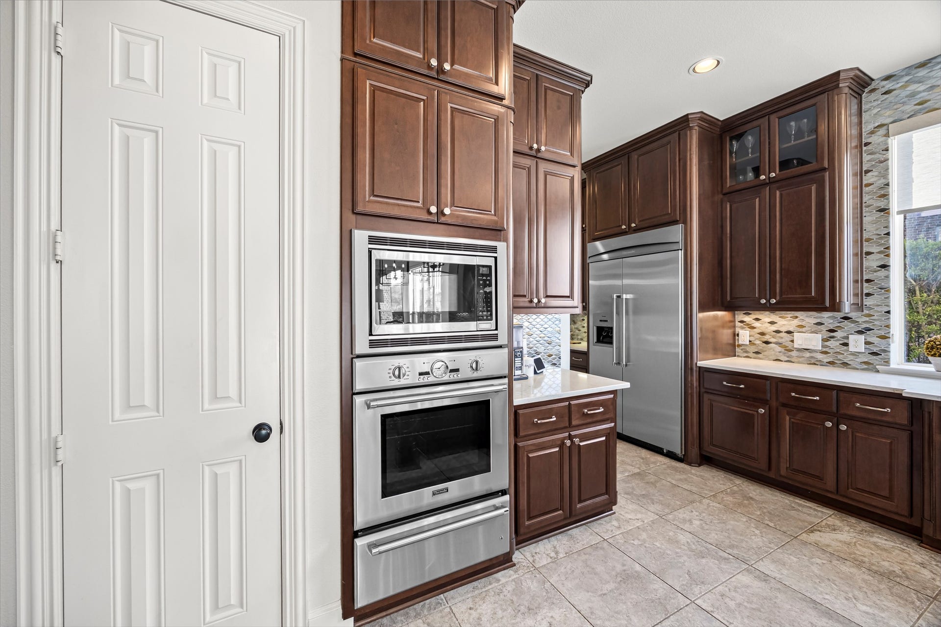 8642 Chickasaw Plum Way, Katy, TX 77494 Kitchen featuring built-in wall oven and microwave, stainless steel appliances, and abundant cabinetry. Thermador oven, microwave, and warmer (electric). New quartz countertops and backsplash (2024).
