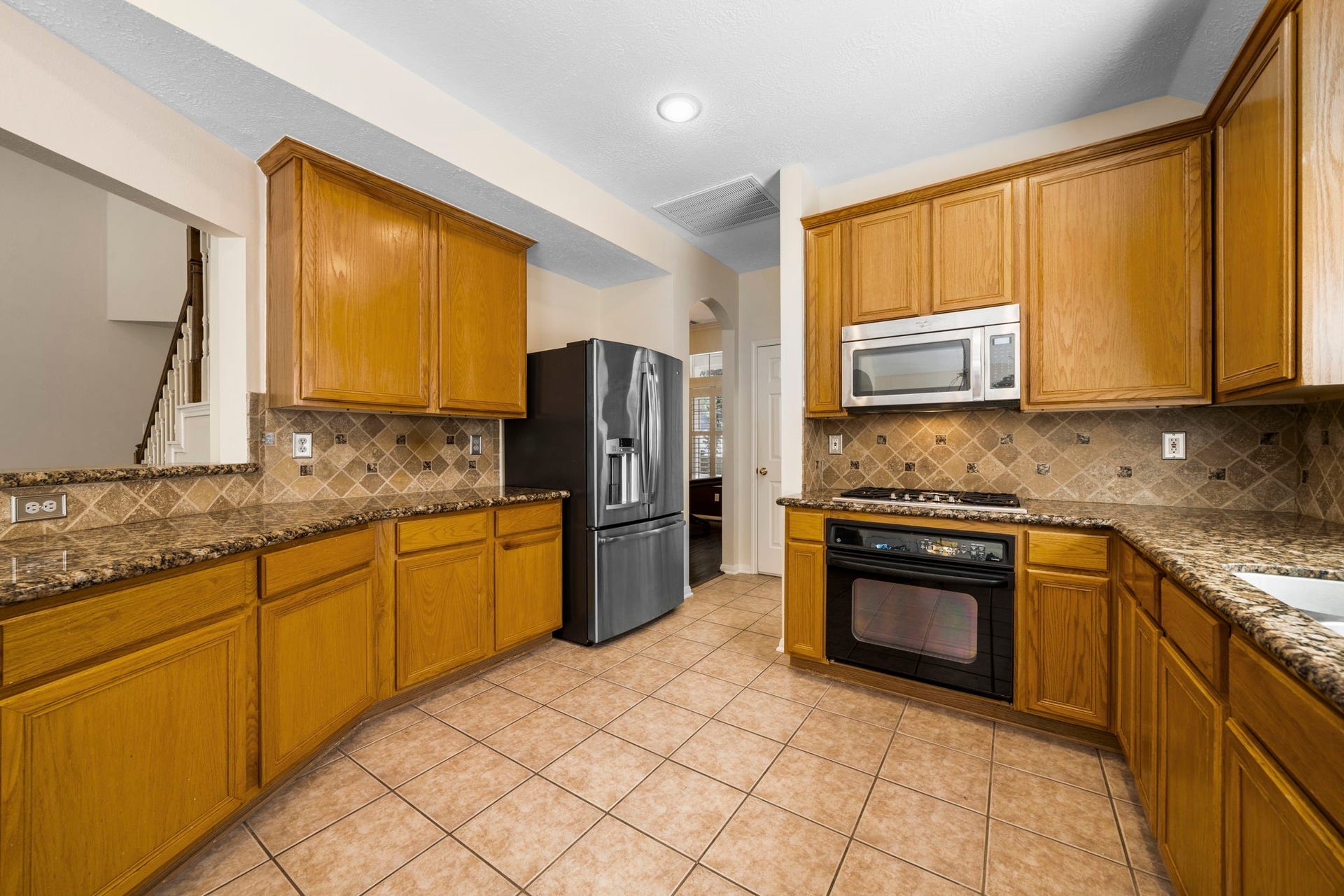 Spacious kitchen featuring charming wood cabinetry and granite countertops.