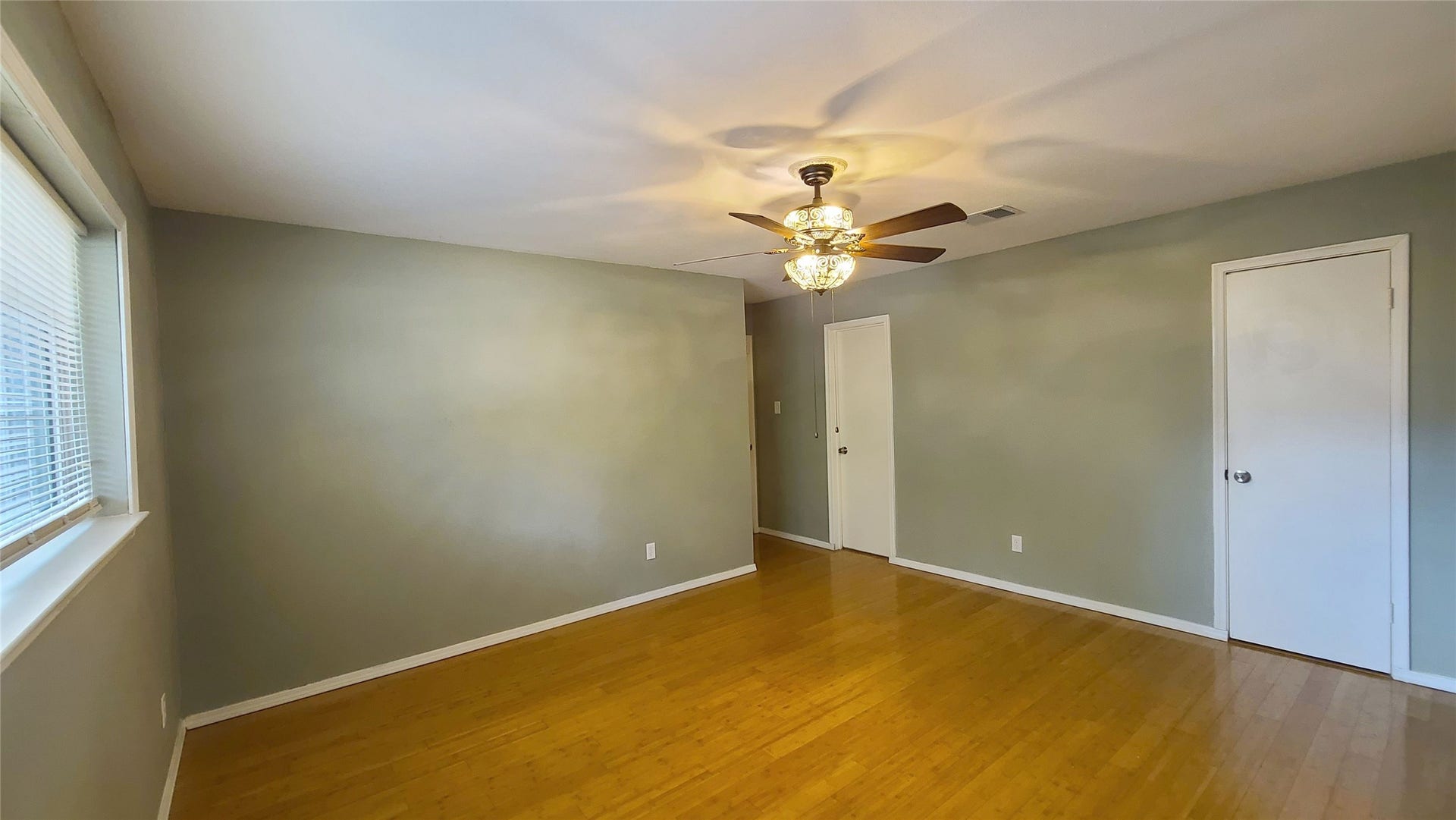 902 Ashford Parkway, Houston, TX 77077 Discover a spacious bedroom featuring warm bamboo wood floors, a stylish ceiling fan, and soft natural light streaming through the window, creating a serene retreat.