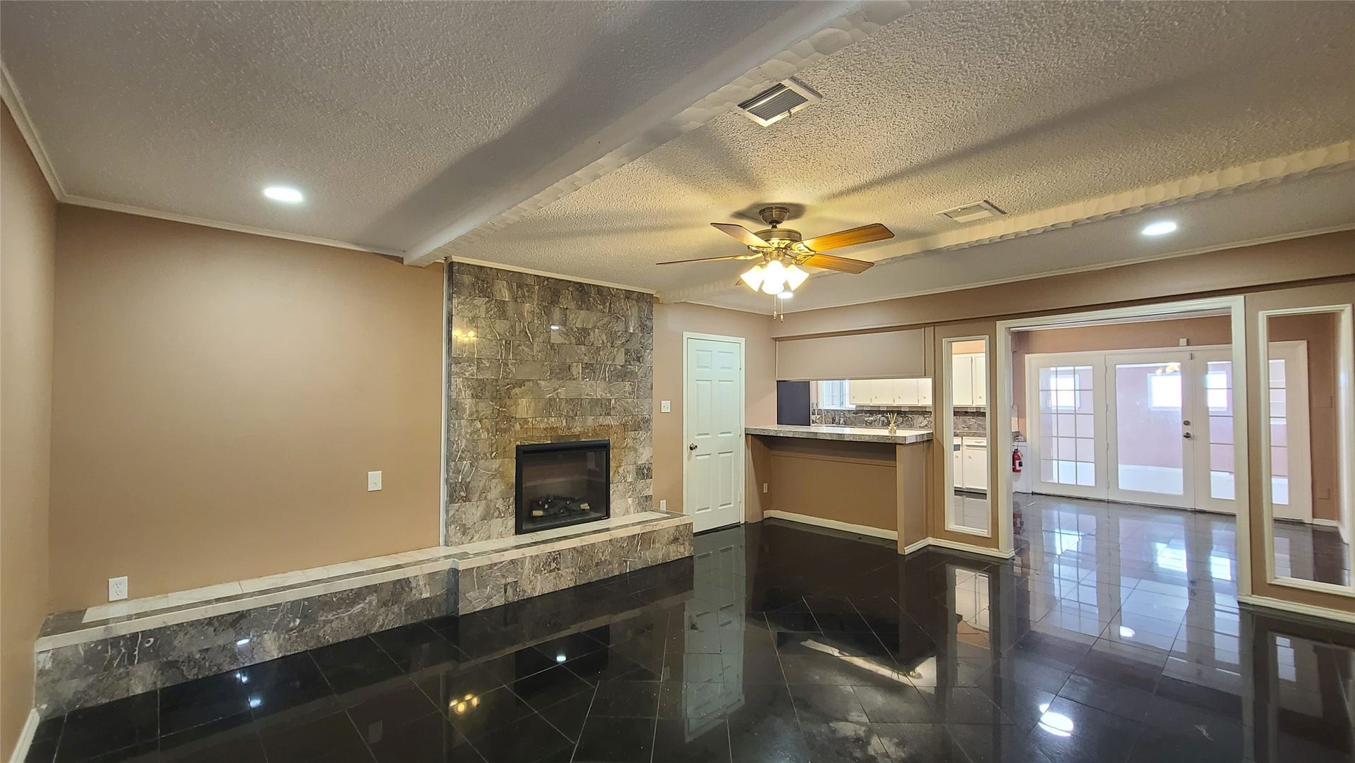 902 Ashford Parkway, Houston, TX 77077 Spacious family room with elegant stone fireplace and glossy tile floors, seamlessly connected to the kitchen, with the convenience of a full bath vanity just behind for added functionality.