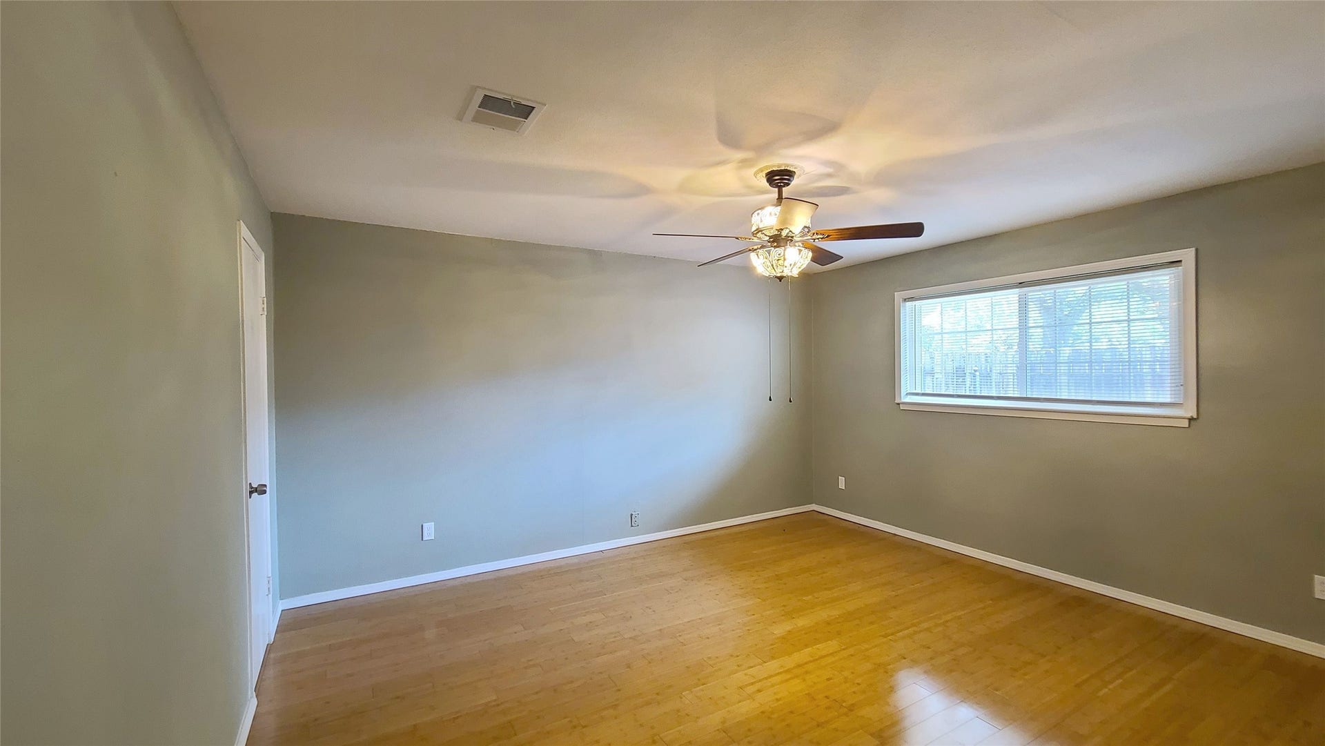 902 Ashford Parkway, Houston, TX 77077 Bright and welcoming bedroom featuring sleek bamboo wood floors, ample closet space, and abundant natural light streaming through large windows for a serene and airy retreat.