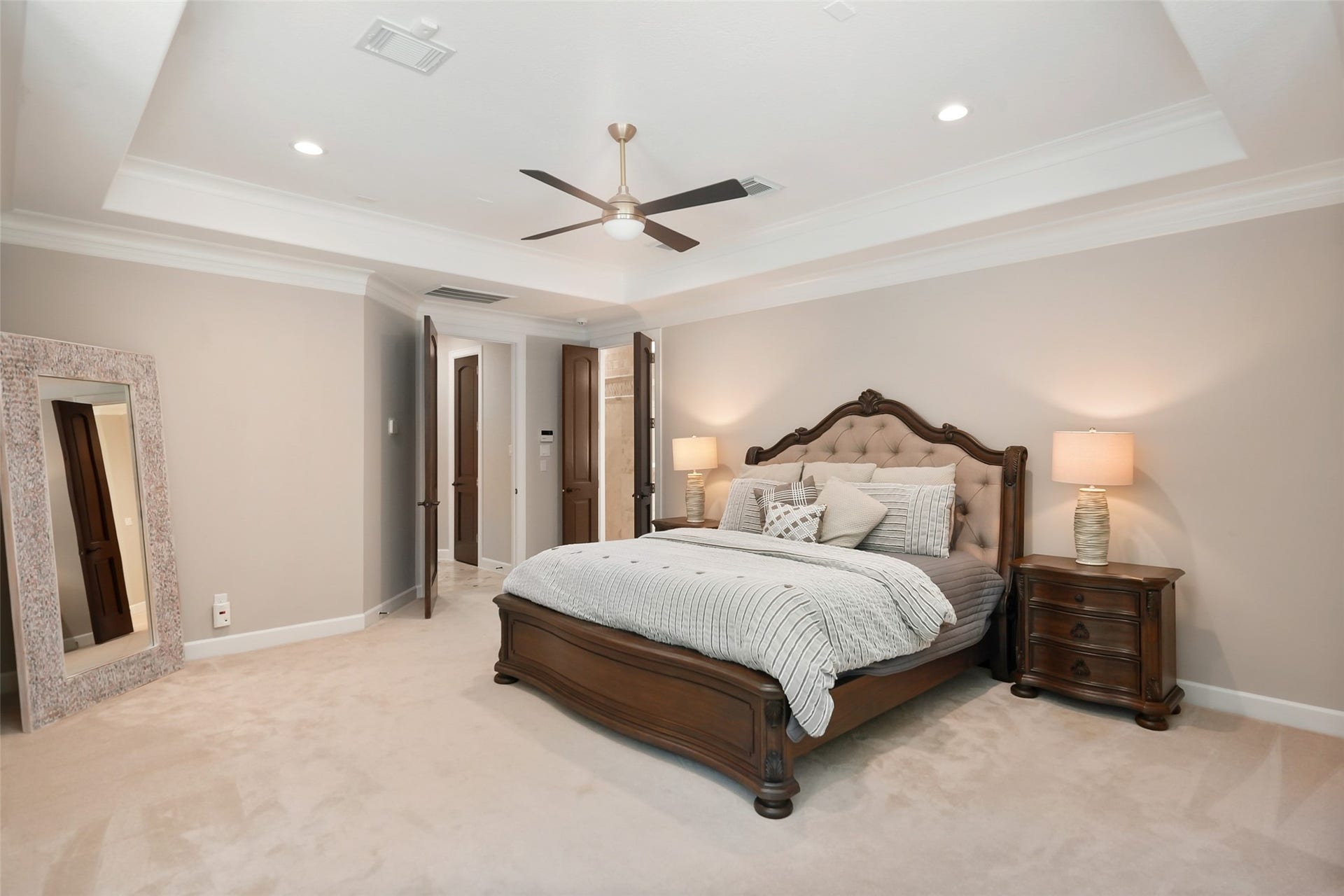 19 Harmony Links Place, The Woodlands, TX 77382 The spacious primary bedroom reveals solid-core double doors to a luxurious en-suite bathroom, creating a private retreat for rest and relaxation!