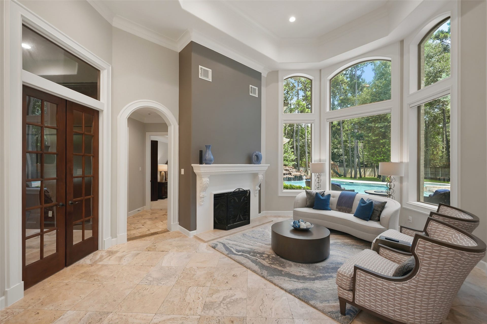 19 Harmony Links Place, The Woodlands, TX 77382 Another view of the formal living room featuring a cozy fireplace! Just beyond the formal living room, the primary bedroom is tucked away on its own wing!