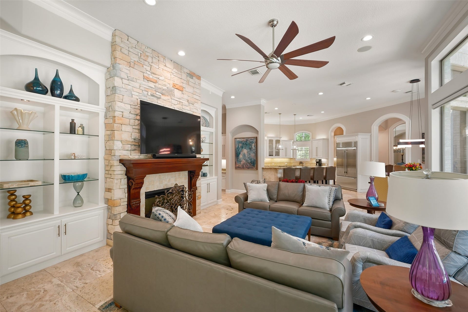 19 Harmony Links Place, The Woodlands, TX 77382 The light-filled and welcoming living room boasts a charming fireplace, perfect for cozy nights, along with built-in cabinetry to house the media system.
