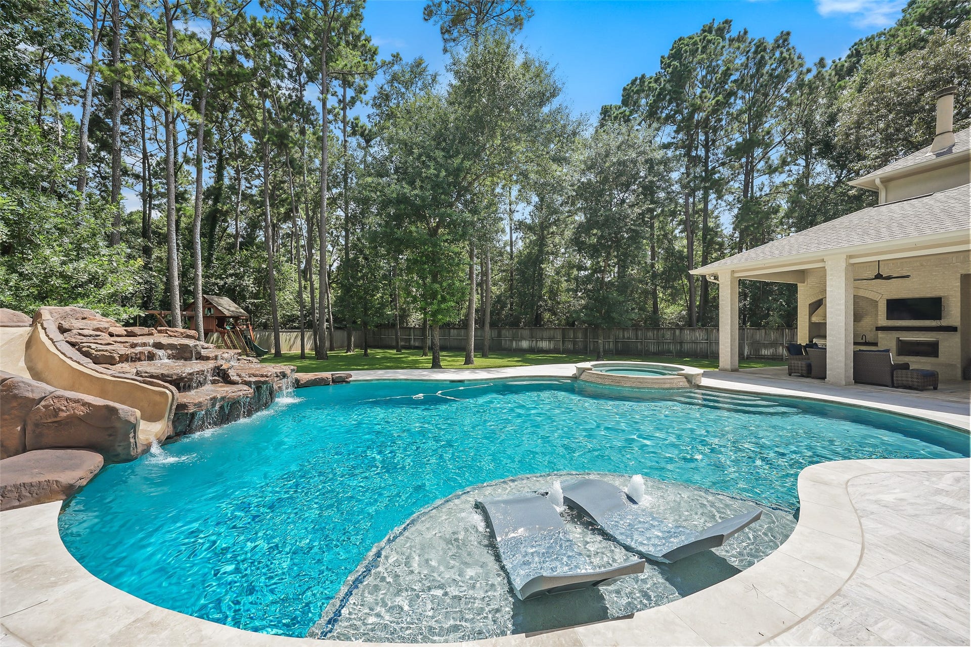 19 Harmony Links Place, The Woodlands, TX 77382 The impressive nine foot deep pool, complete with a waterfall, waterslide, and diving rock, was completely rebuilt by Township Pools in 2020, creating a stunning backyard retreat!