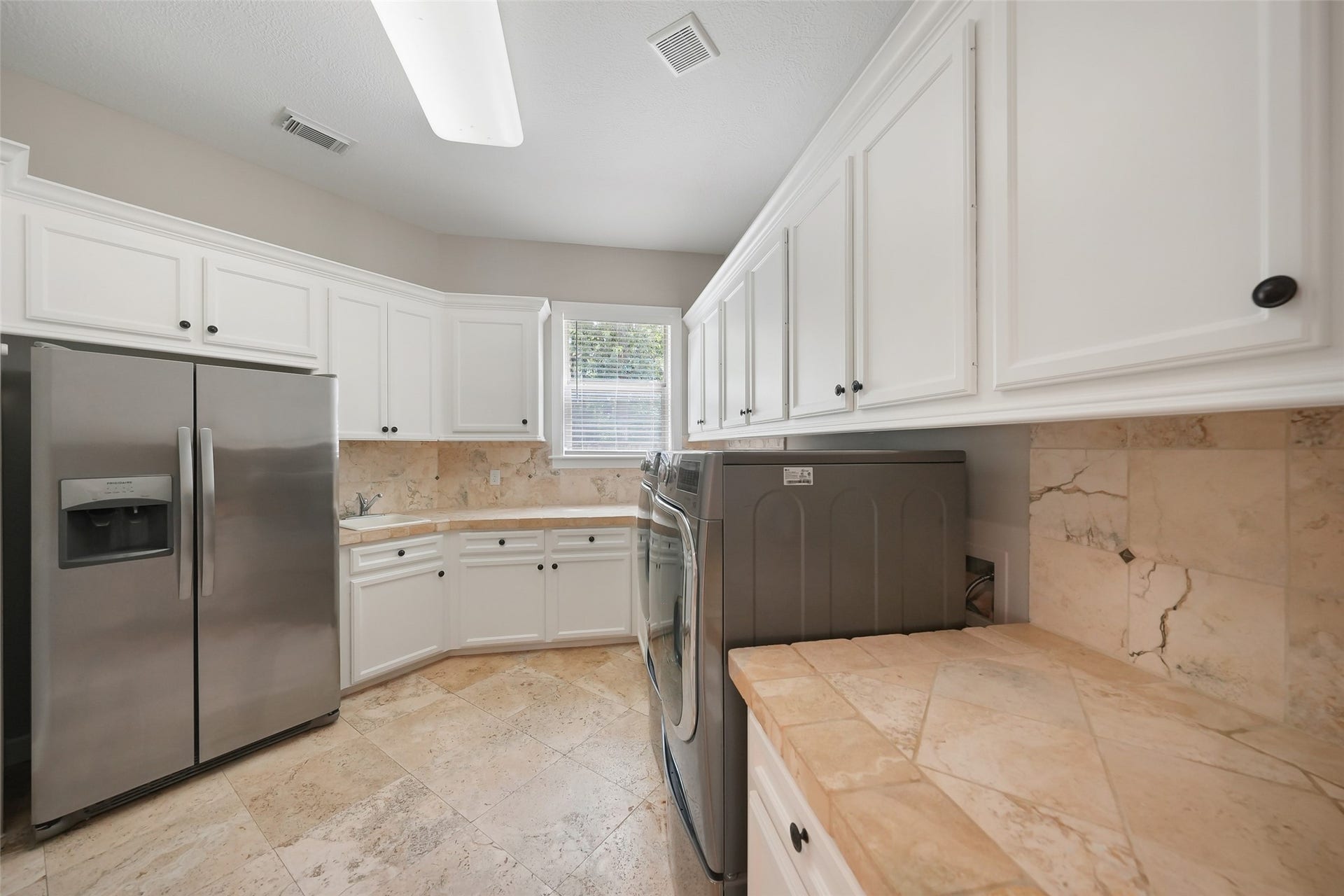 19 Harmony Links Place, The Woodlands, TX 77382 The spacious first floor laundry room is thoughtfully designed with abundant cabinetry for storage, a convenient utility sink, and ample space to accommodate a full size refrigerator! A large window provides natural light in this hard working space!