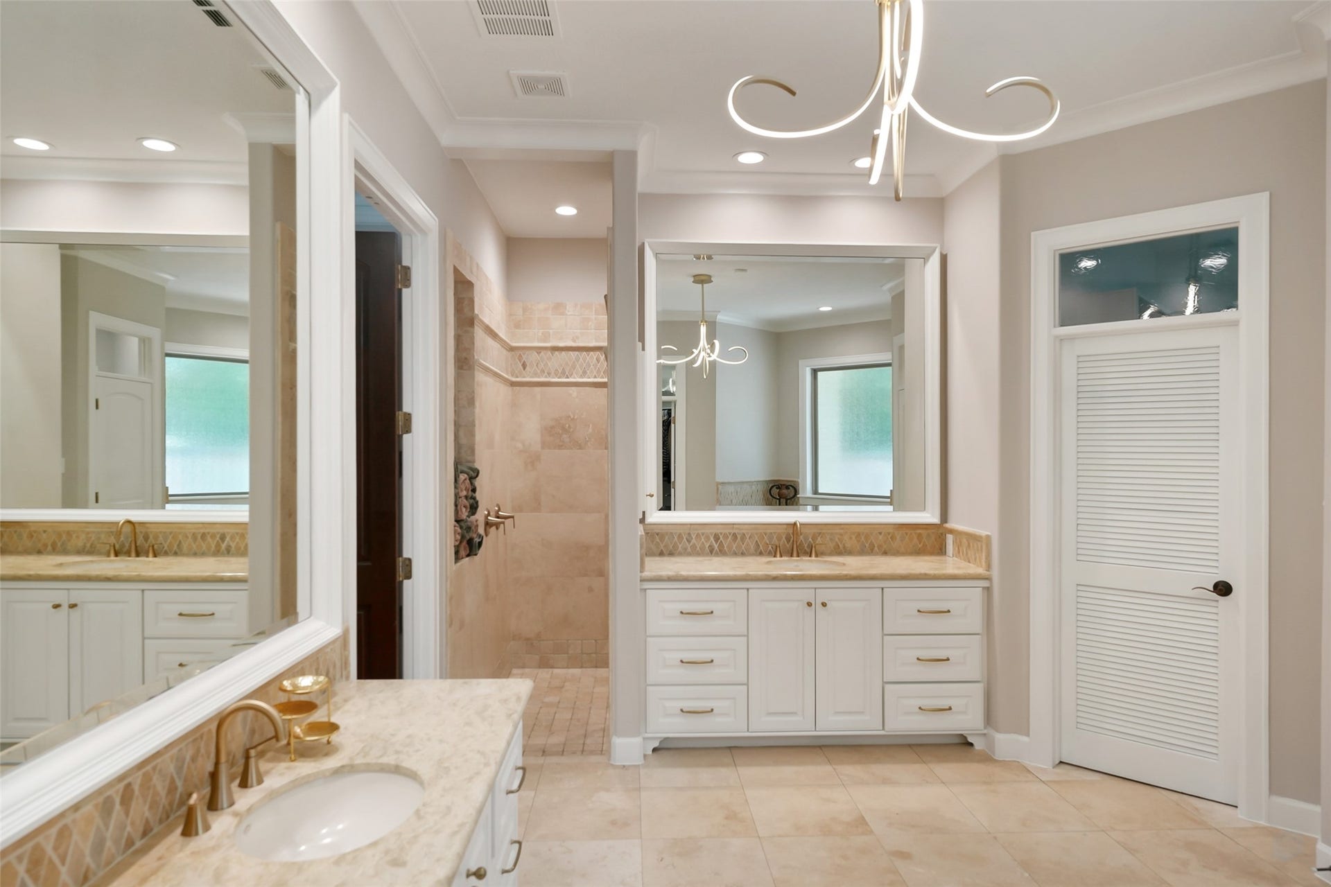 19 Harmony Links Place, The Woodlands, TX 77382 A walk-in spacious shower enhances the indulgence of the spa-like space. Two separate vanities are nestled below large framed mirrors that reflect the natural light and enhance the spaciousness. Natural stone counters and gold-toned hardware create a classic look.
