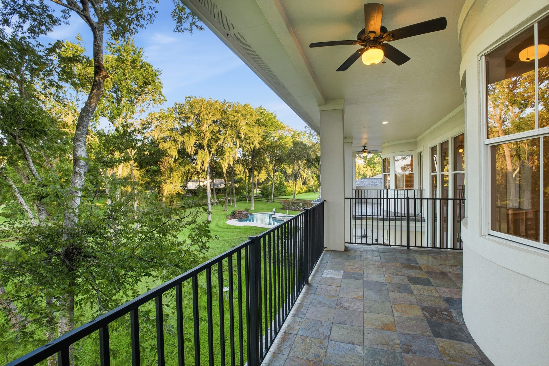 3518 River Forest Drive, Richmond, TX 77406 Expansive balcony with elegant tile flooring, ceiling fans, and serene views of lush greenery and a sparkling pool.